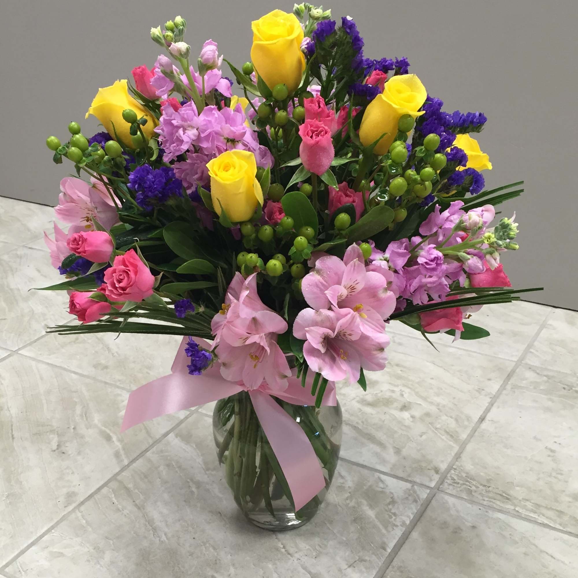 A mixed warm colors bouquet of flowers in a clear glass bud A mixed warm colors bouquet of flowers in a clear glass bud