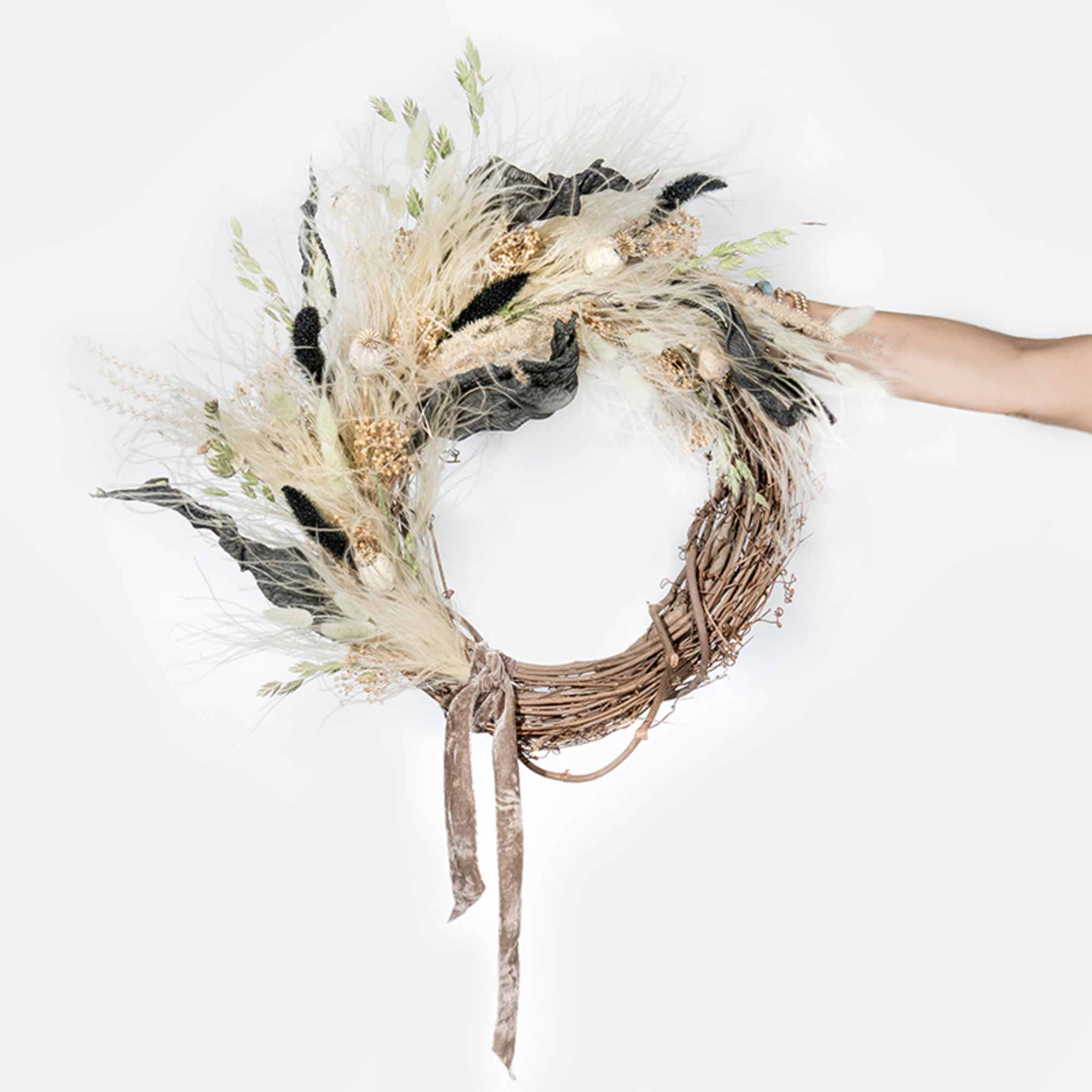 This hand-made, asymmetrical wreath includes an assortment of dried florals in shades