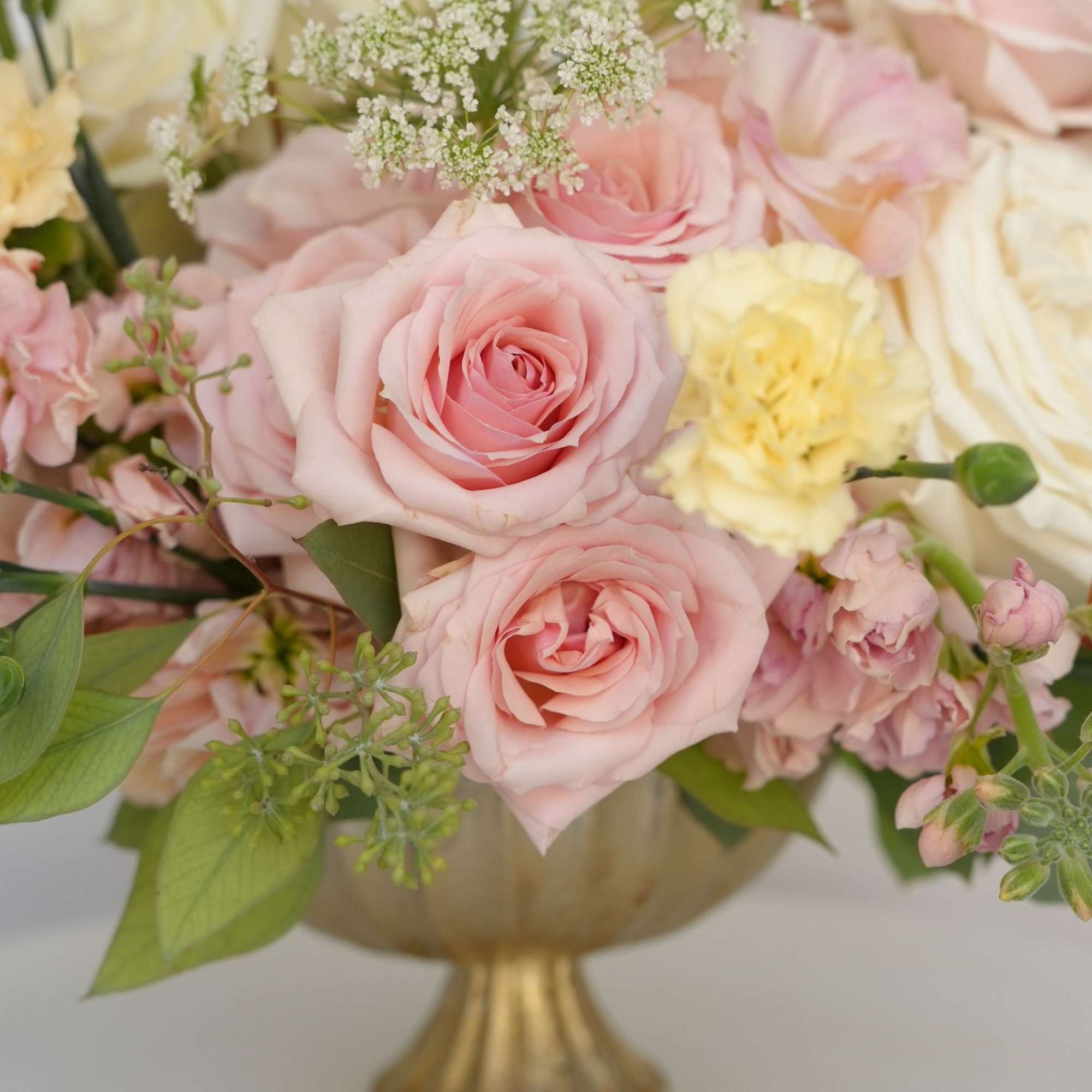 A lush floral arrangement displayed in an elegant golden vessel with soft A lush floral arrangement displayed in an elegant golden vessel with soft
