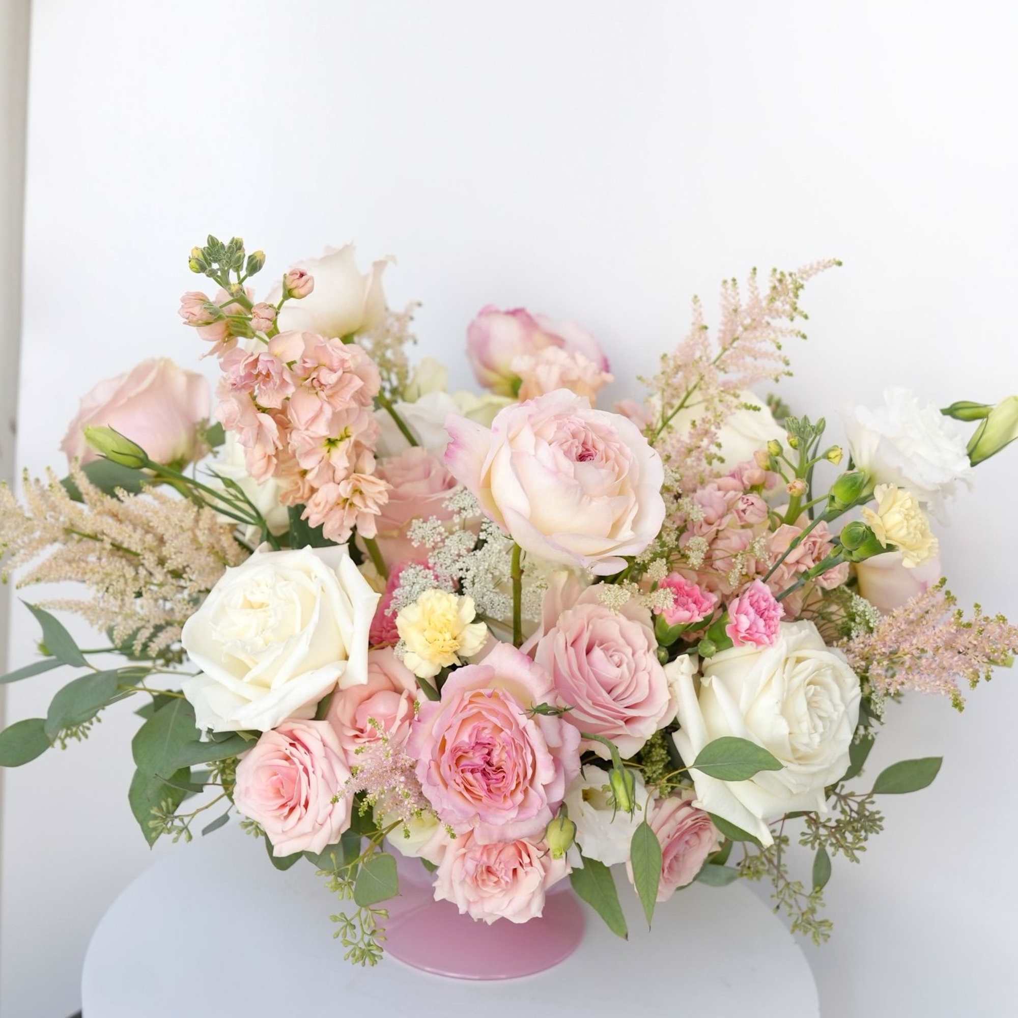 A lush floral arrangement displayed in an elegant golden vessel with soft A lush floral arrangement displayed in an elegant golden vessel with soft