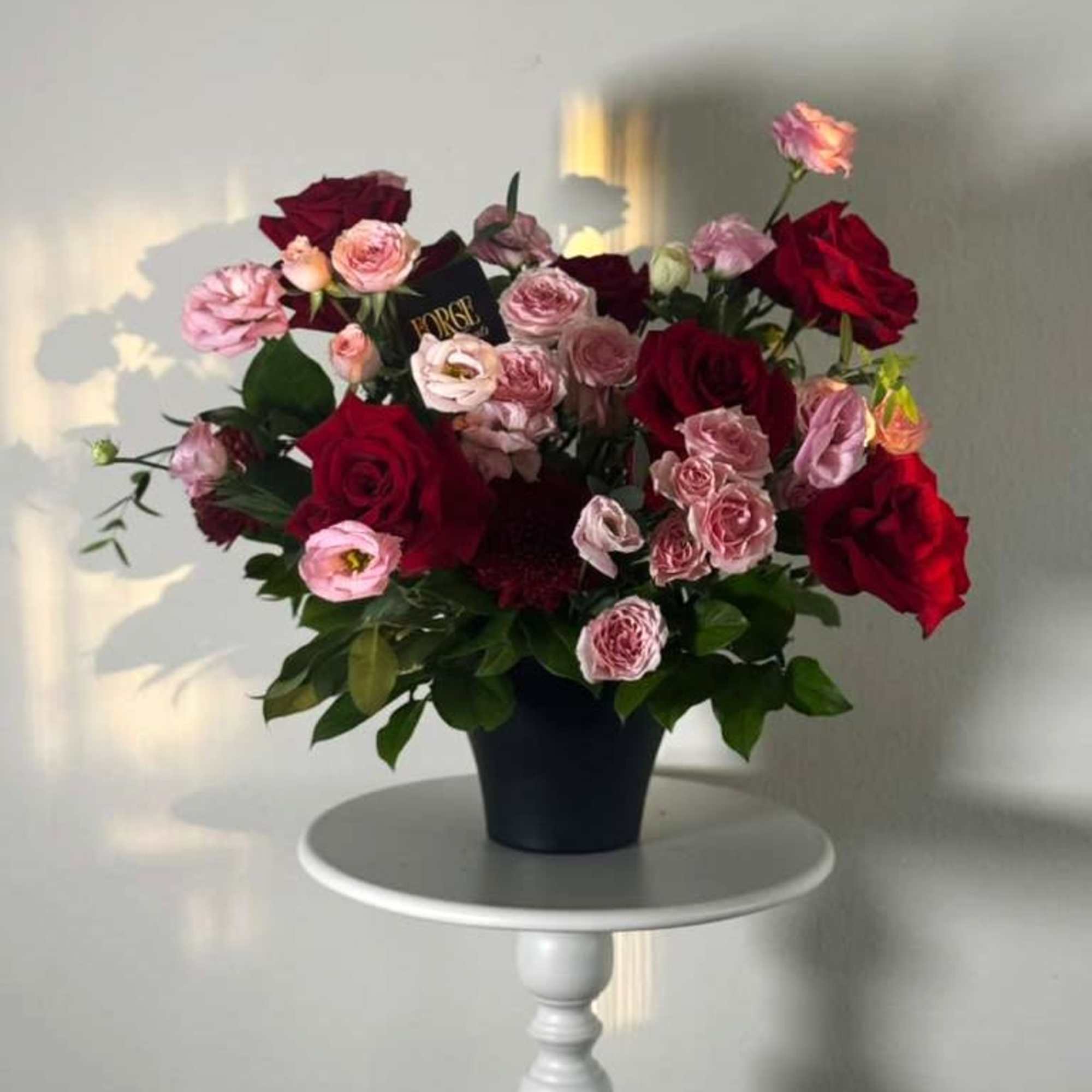 Deep red roses and soft pink blooms arranged in a sleek black
