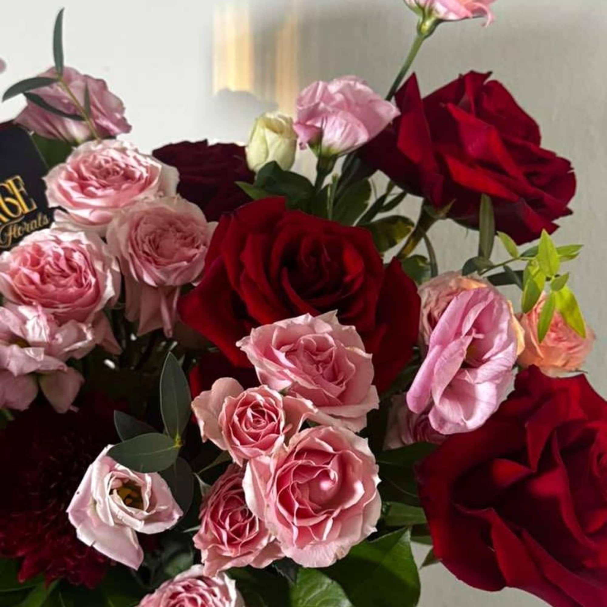 Deep red roses and soft pink blooms arranged in a sleek black