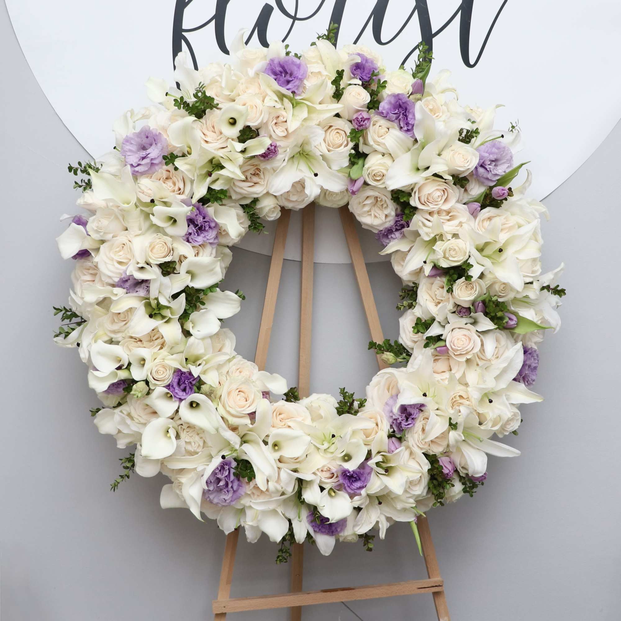 This sympathy wreath is made with white lilies, callas, and roses. It&#039;s