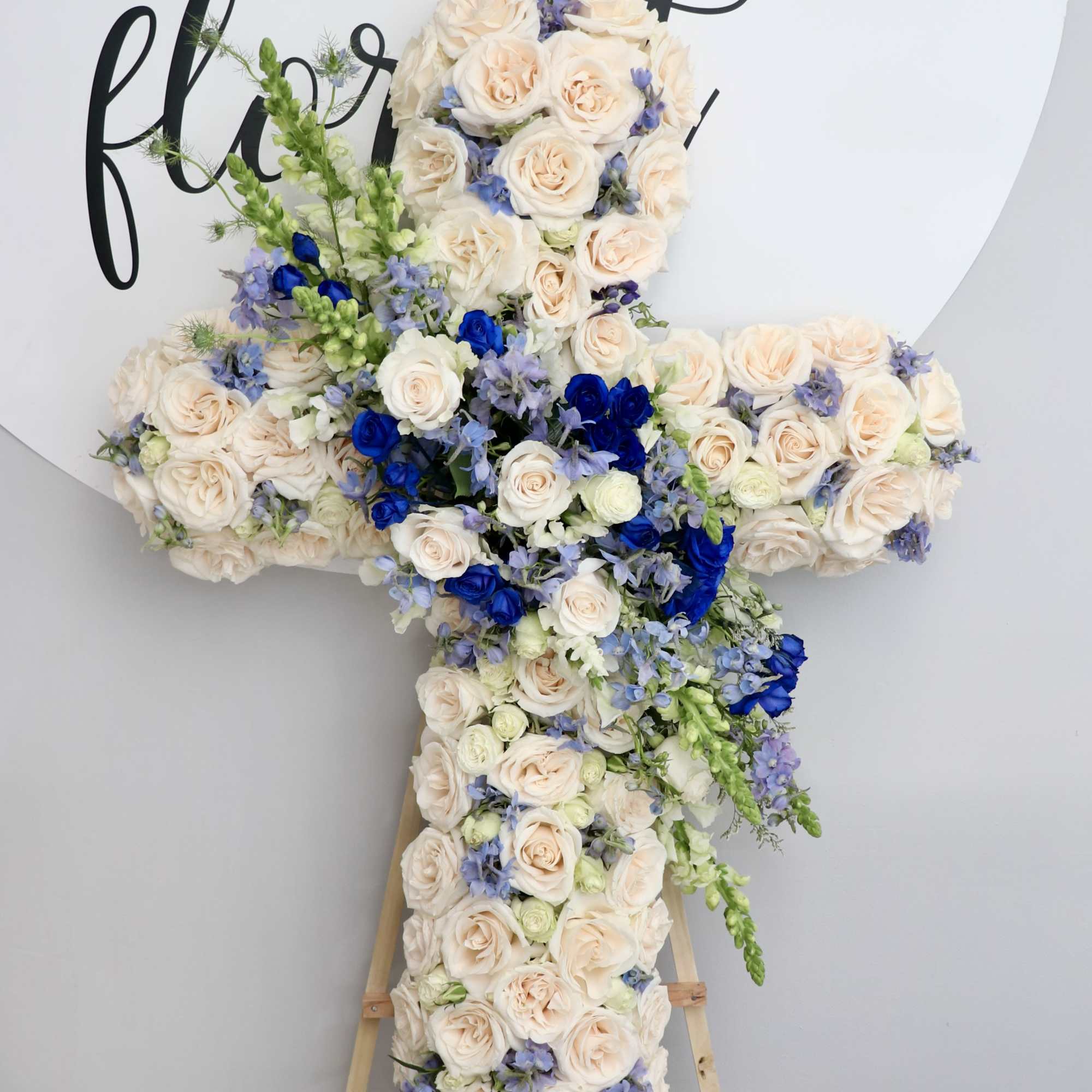 This sympathy cross is made with white roses and accented with shades