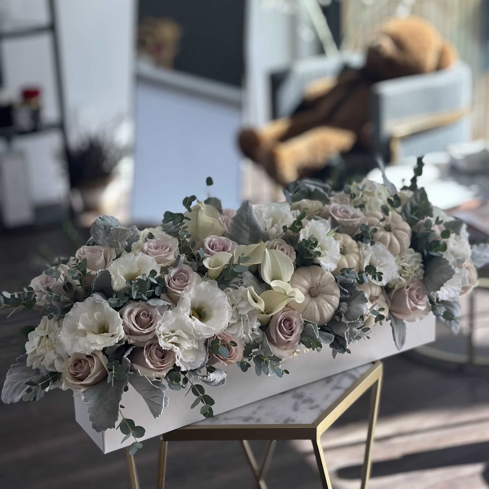 A refined modern arrangement featuring soft neutral blooms and mini ivory pumpkins