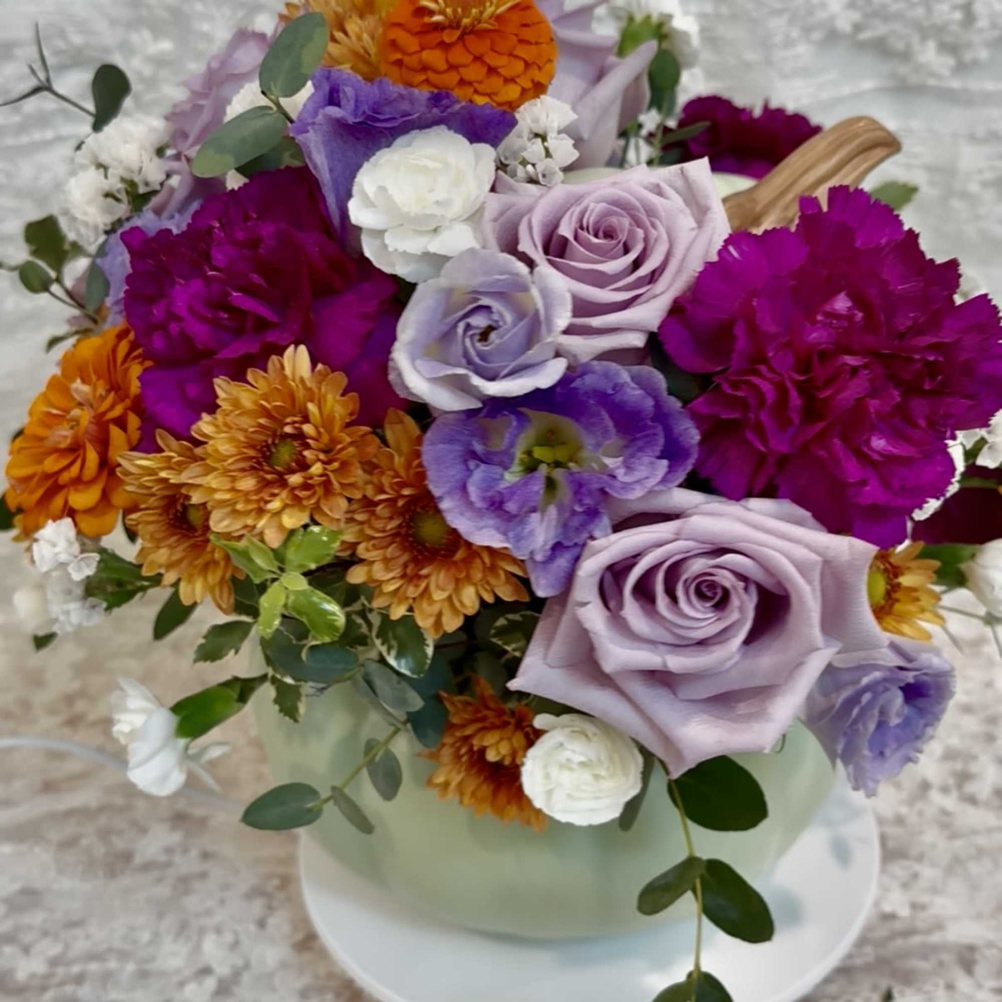 Sage ceramic pumpkin with lid filled with purple tone flowers with a