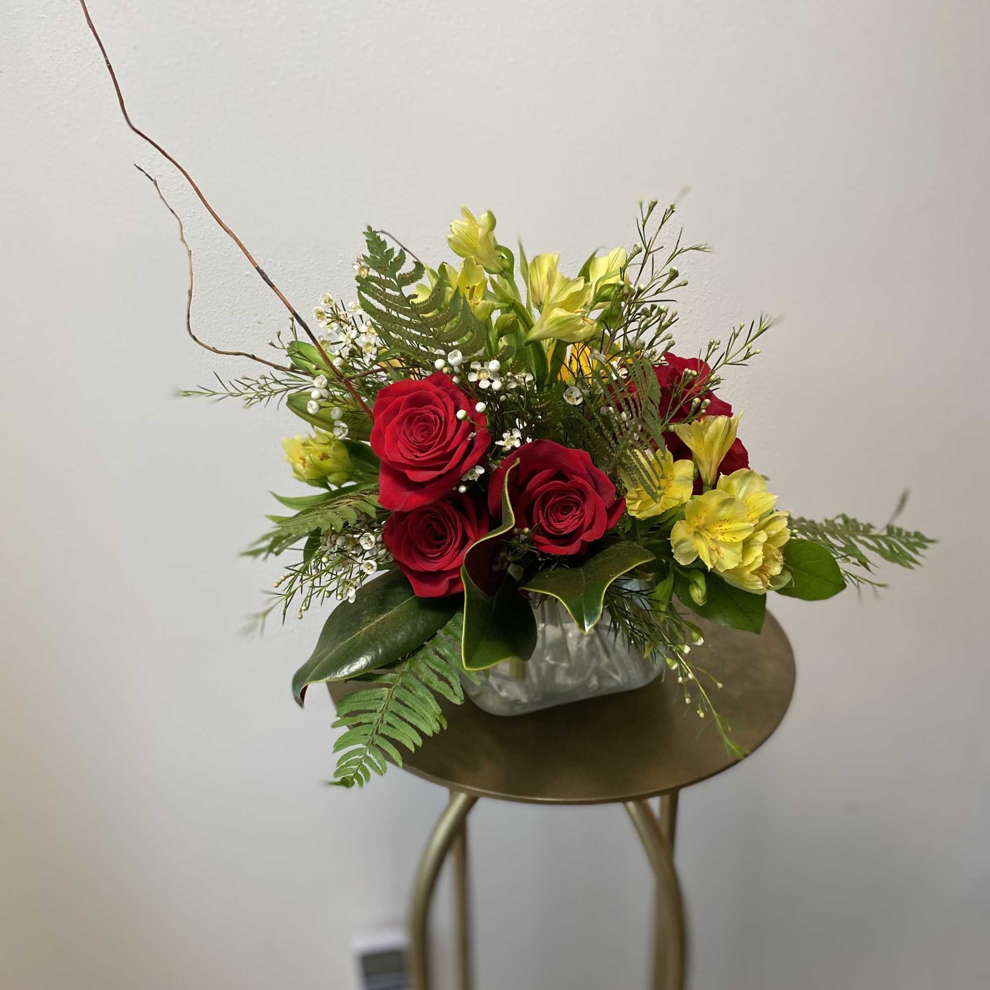 Roses, lilies, and sunflowers, nestled seasonal greens, accented with Autumn branches. A Roses, lilies, and sunflowers, nestled seasonal greens, accented with Autumn branches. A