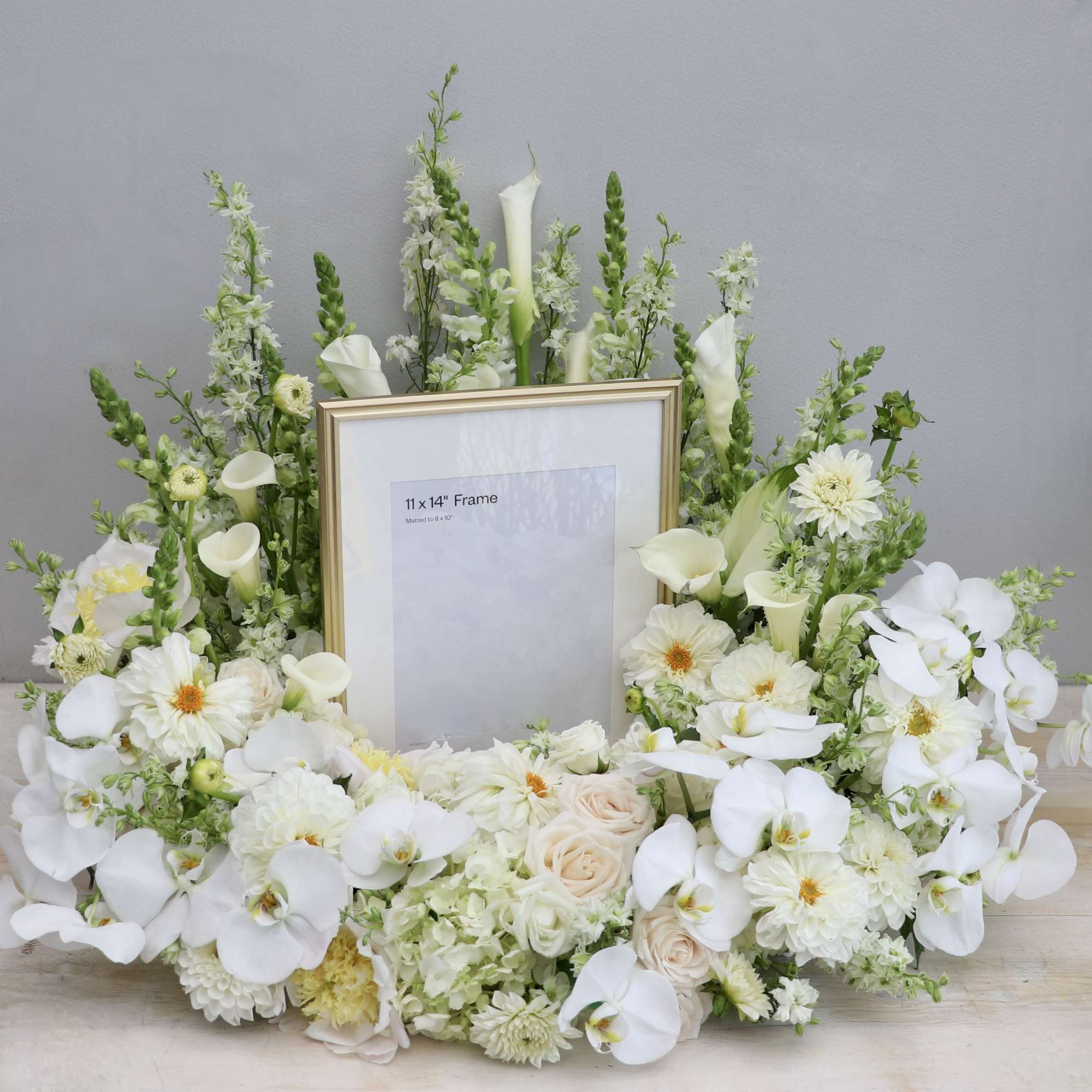 This urn tribute wreath includes a mix of orchids, roses, and seasonal