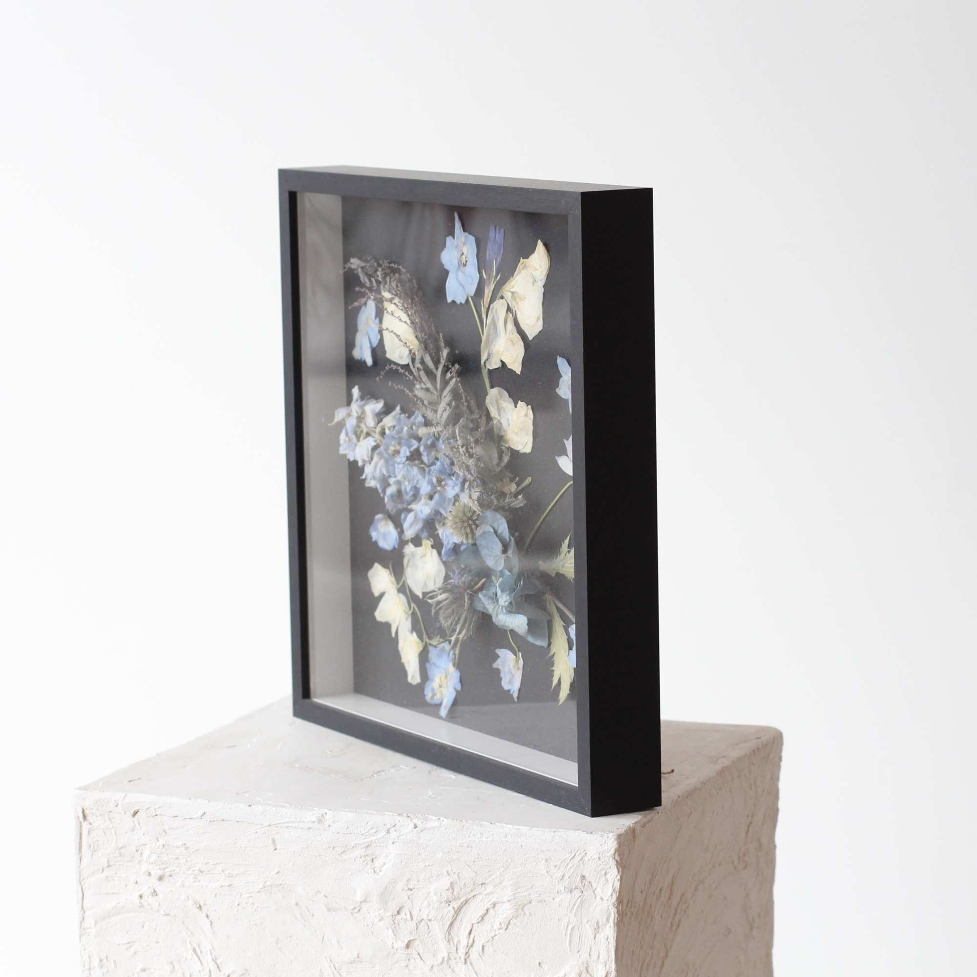 This elegant shadowbox features a stunning arrangement of delicate dried blue flowers