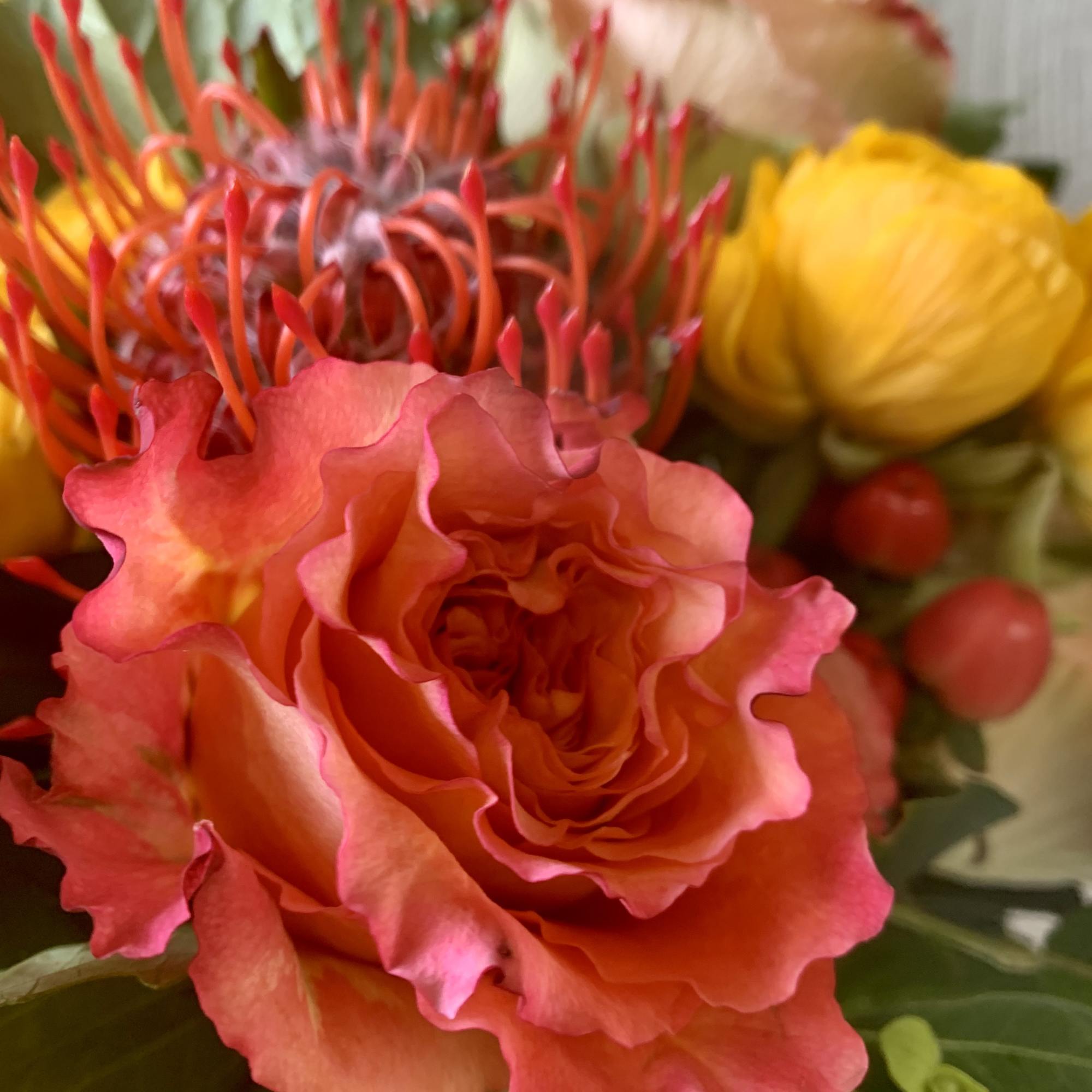 An autumnal vibe of reds, oranges and yellow florals of ranunculus, roses