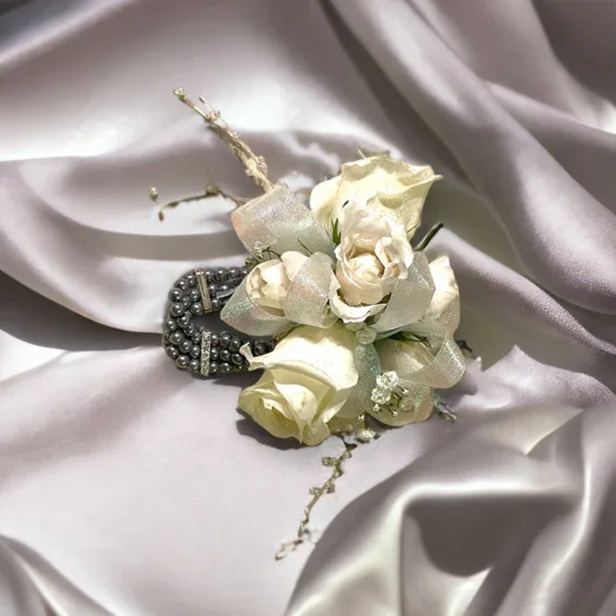 Our florists hand-craft a gorgeous white rose corsage accented with fresh greens Our florists hand-craft a gorgeous white rose corsage accented with fresh greens