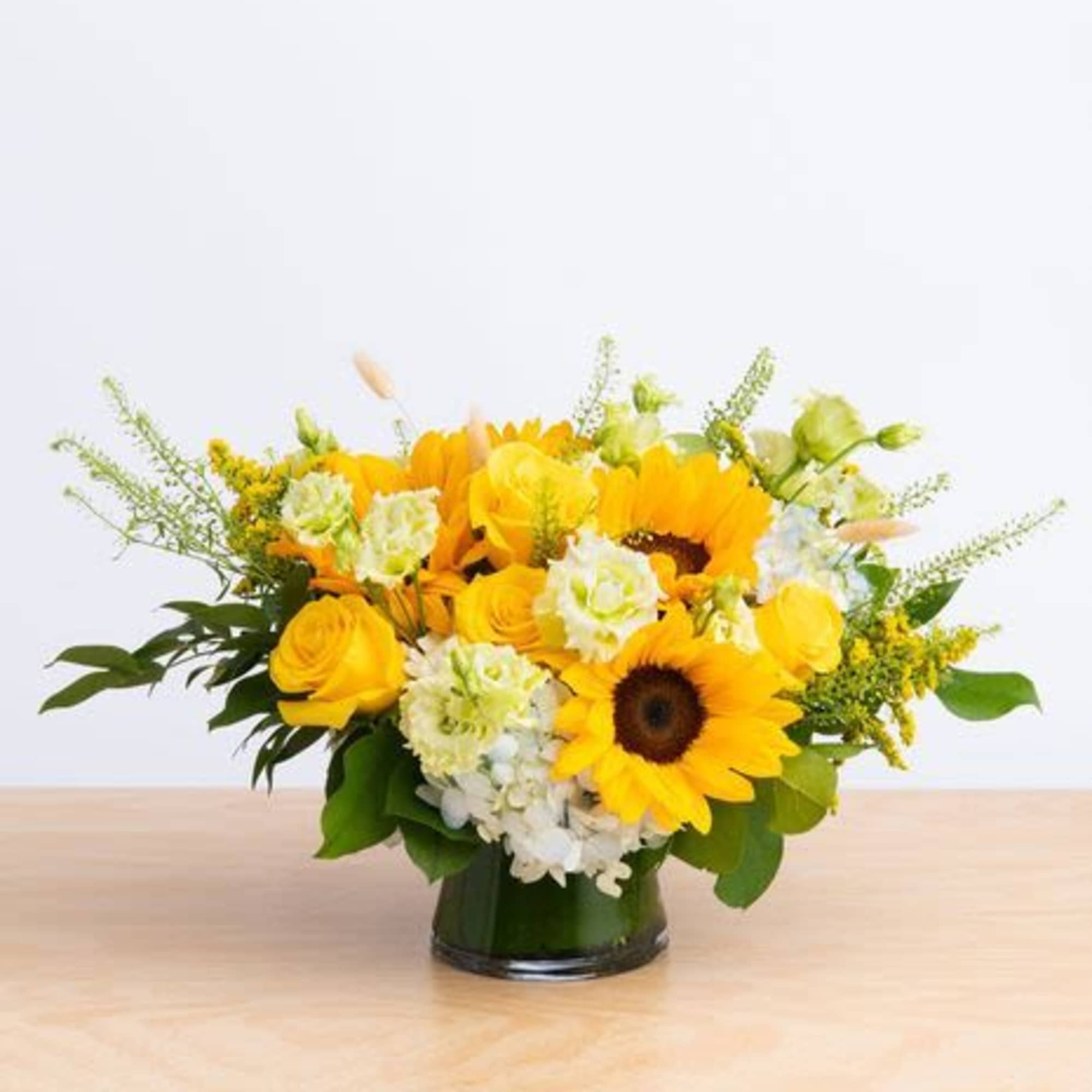 An elegant arrangement featuring roses, spray roses , hydrangeas, berries, greenery .This