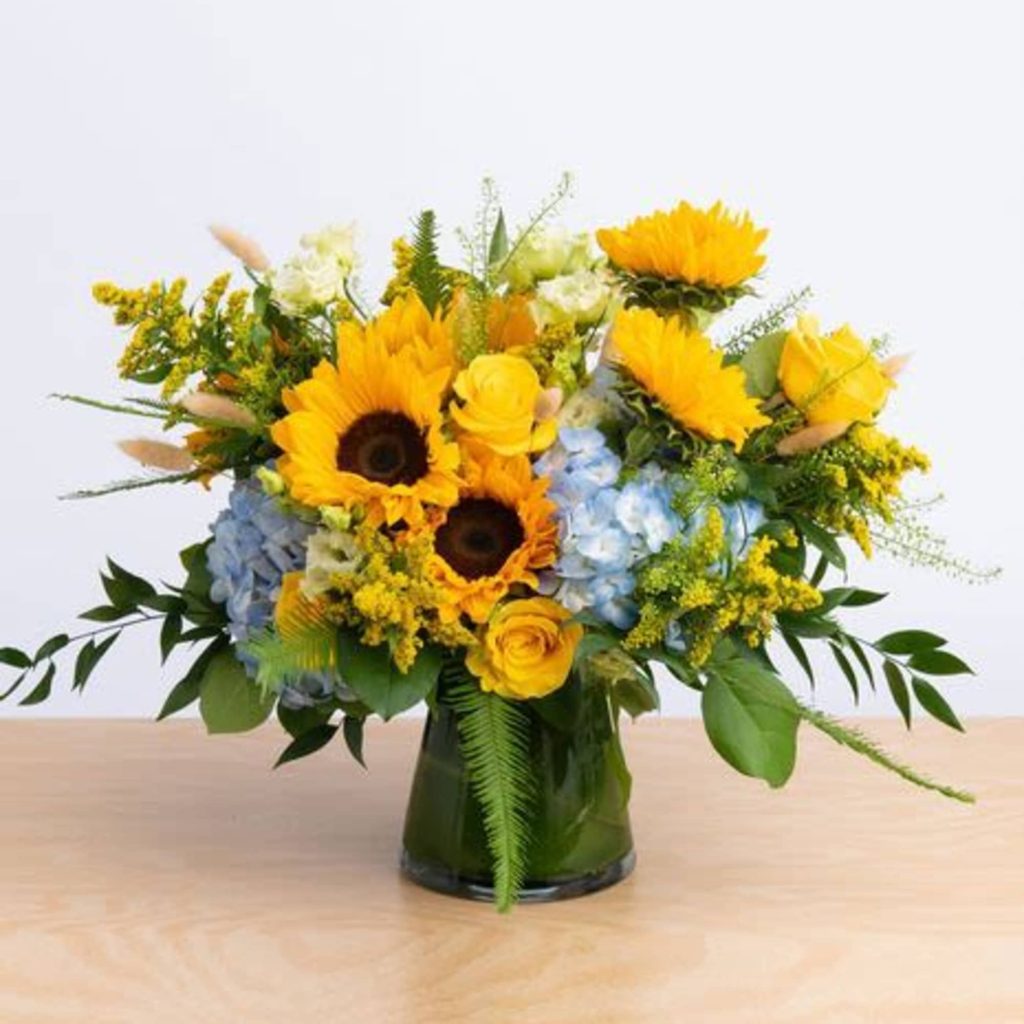 An elegant arrangement featuring roses, spray roses , hydrangeas, berries, greenery .This