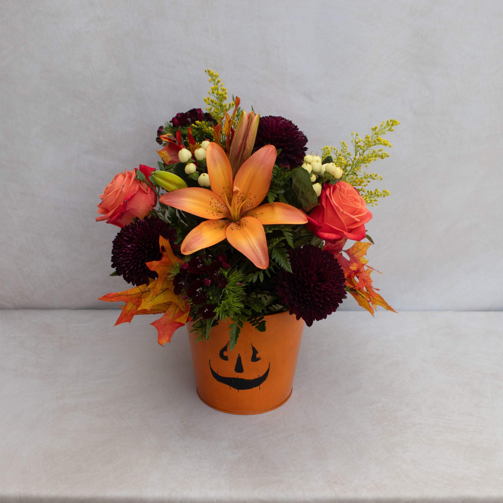 A MIXURE OF FALL FLOWERS IN AN ORANGE METAL TIN WITH A A MIXURE OF FALL FLOWERS IN AN ORANGE METAL TIN WITH A