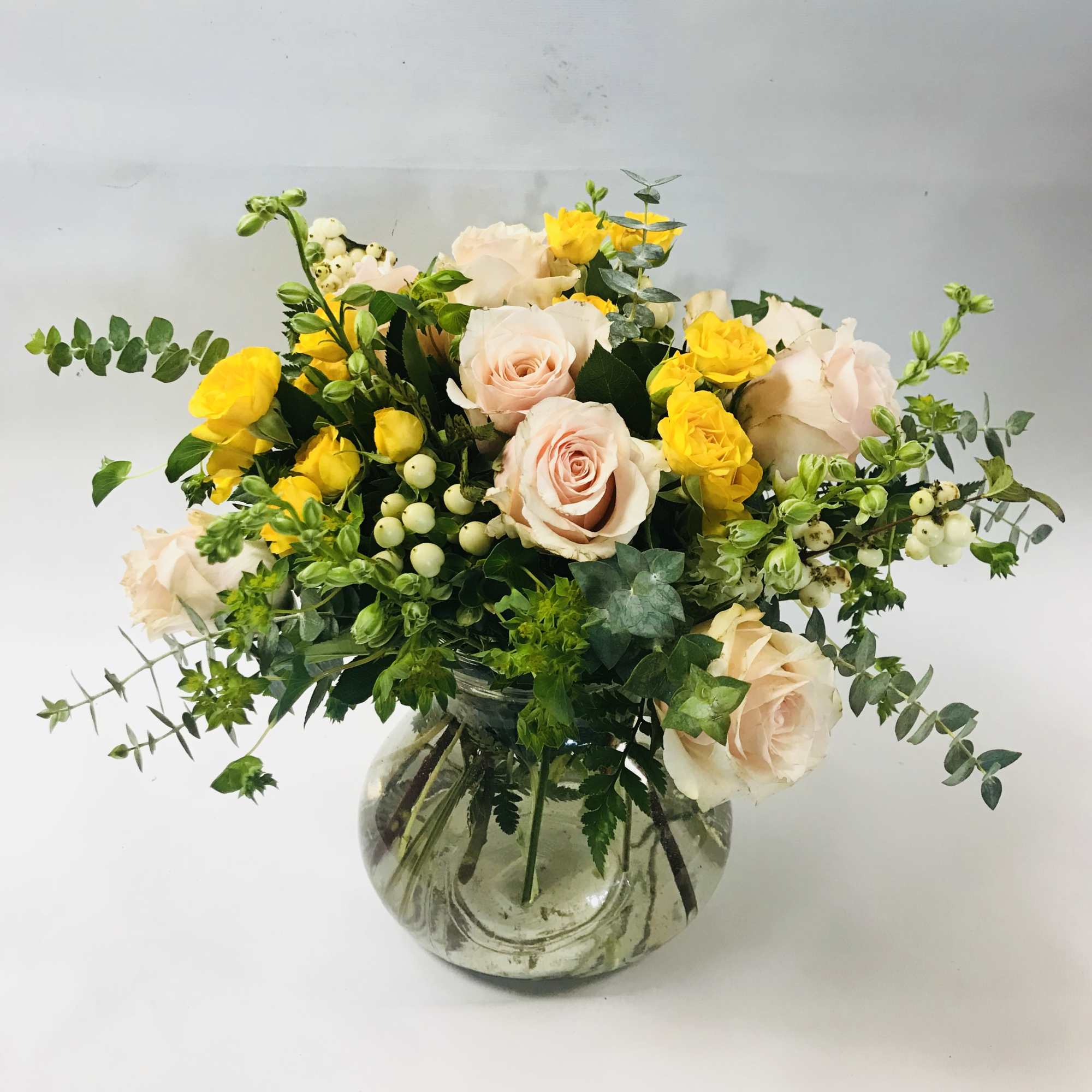 An elegant selection of peach roses, yellow spray roses, larkspur and eucalyptus