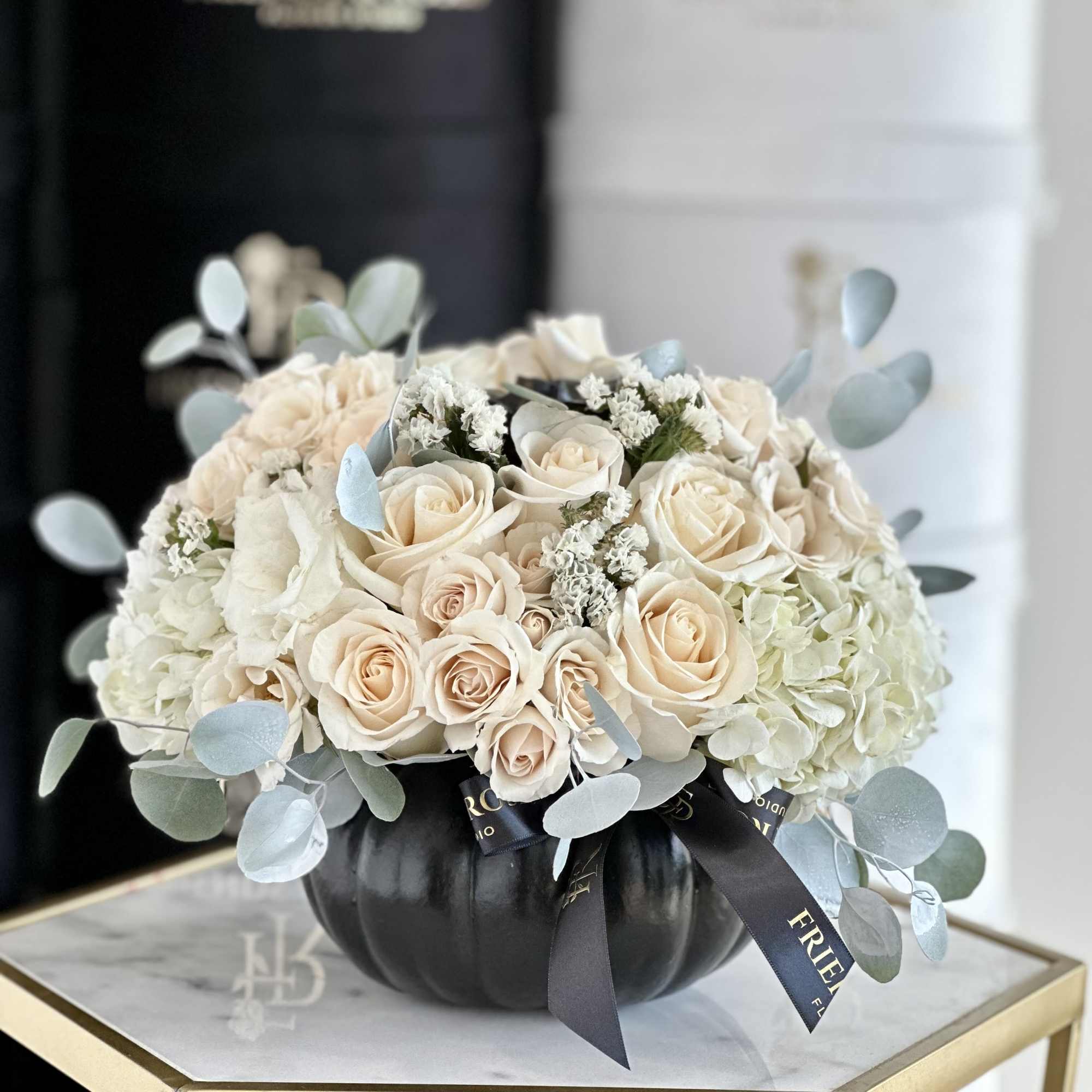 A chic modern arrangement of white roses in a sleek black pumpkin.