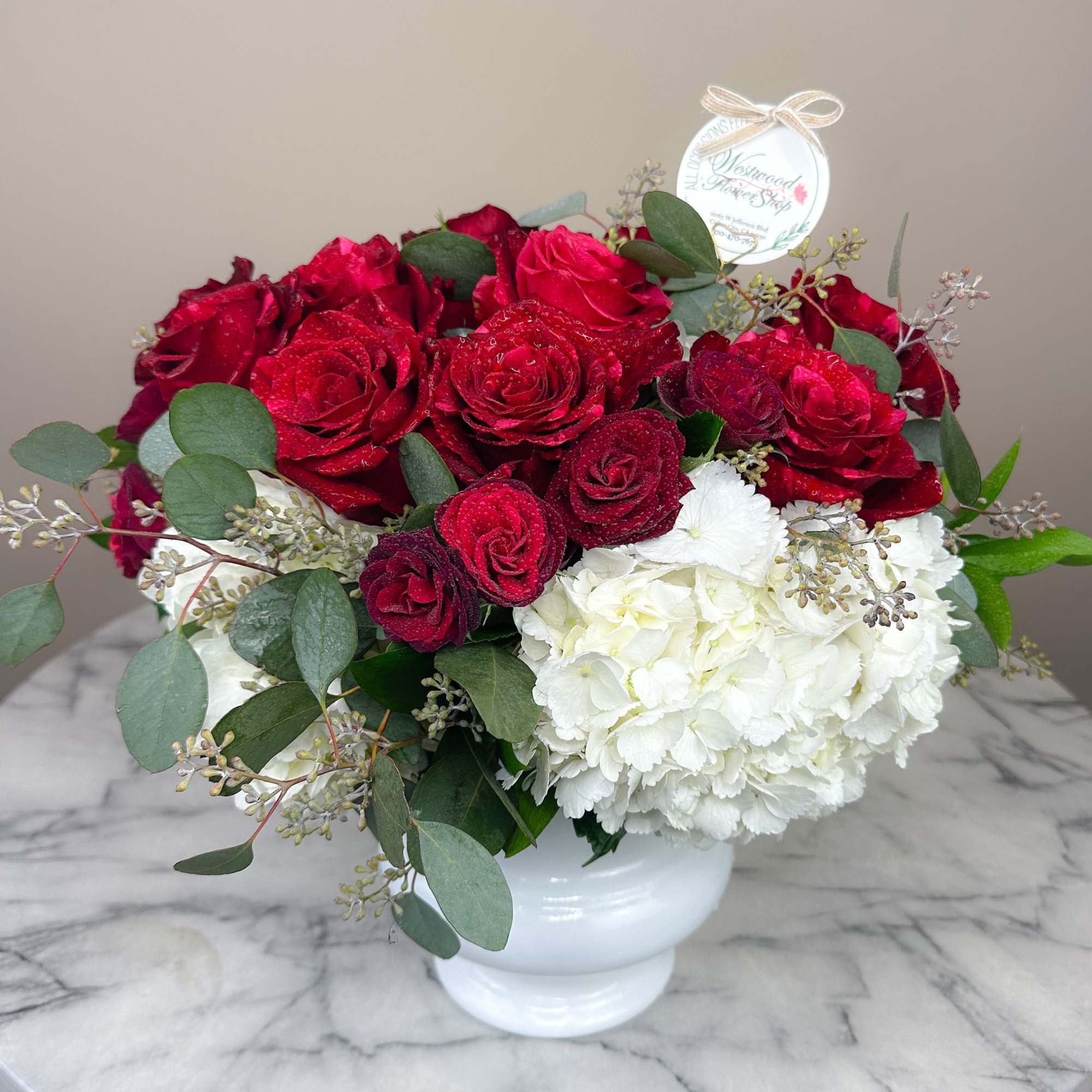 A dozen lush red roses and white hydrangeas designed with fine greenery