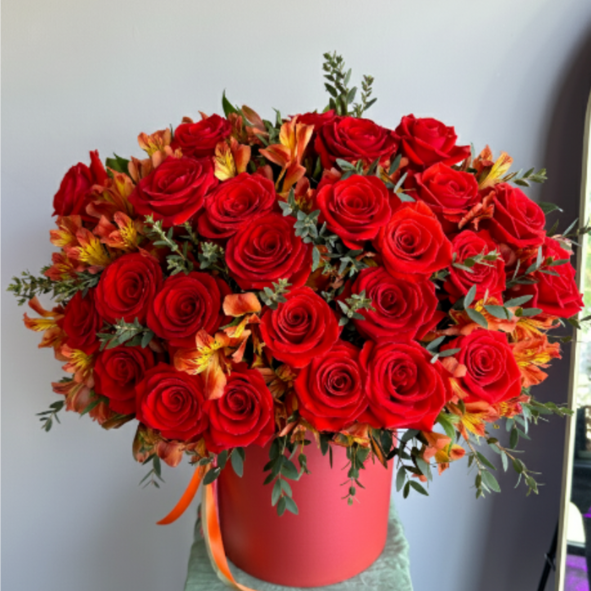 A luxury flower arrangement of premium red garden roses and fiery orange