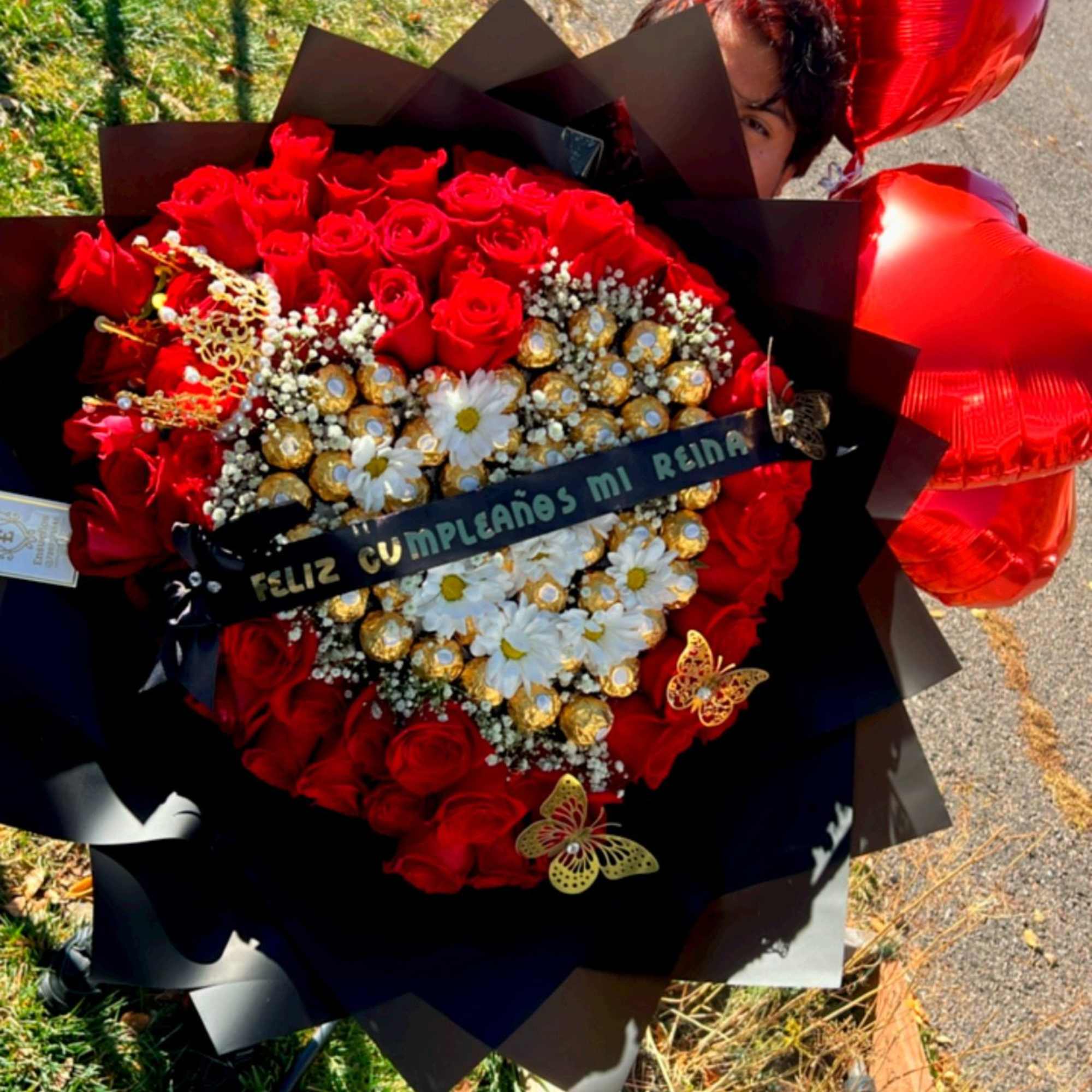 Buchon elaborado con rosas rojas, corona, liston, mariposas artificiales y chocolates ferrero.