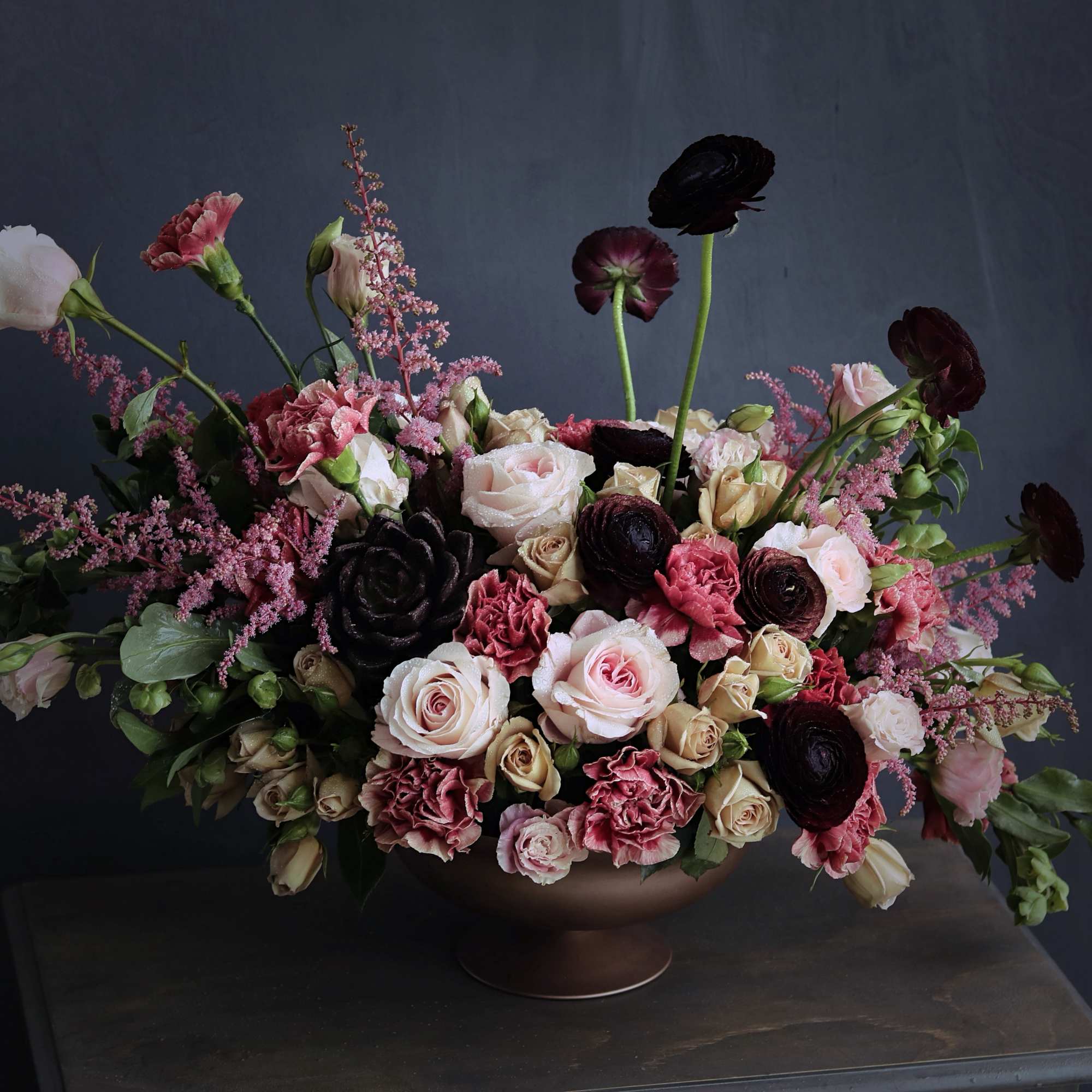 Warm tones of ranunculus, roses, lisianthus, carnations, and succulents beautifully laid out