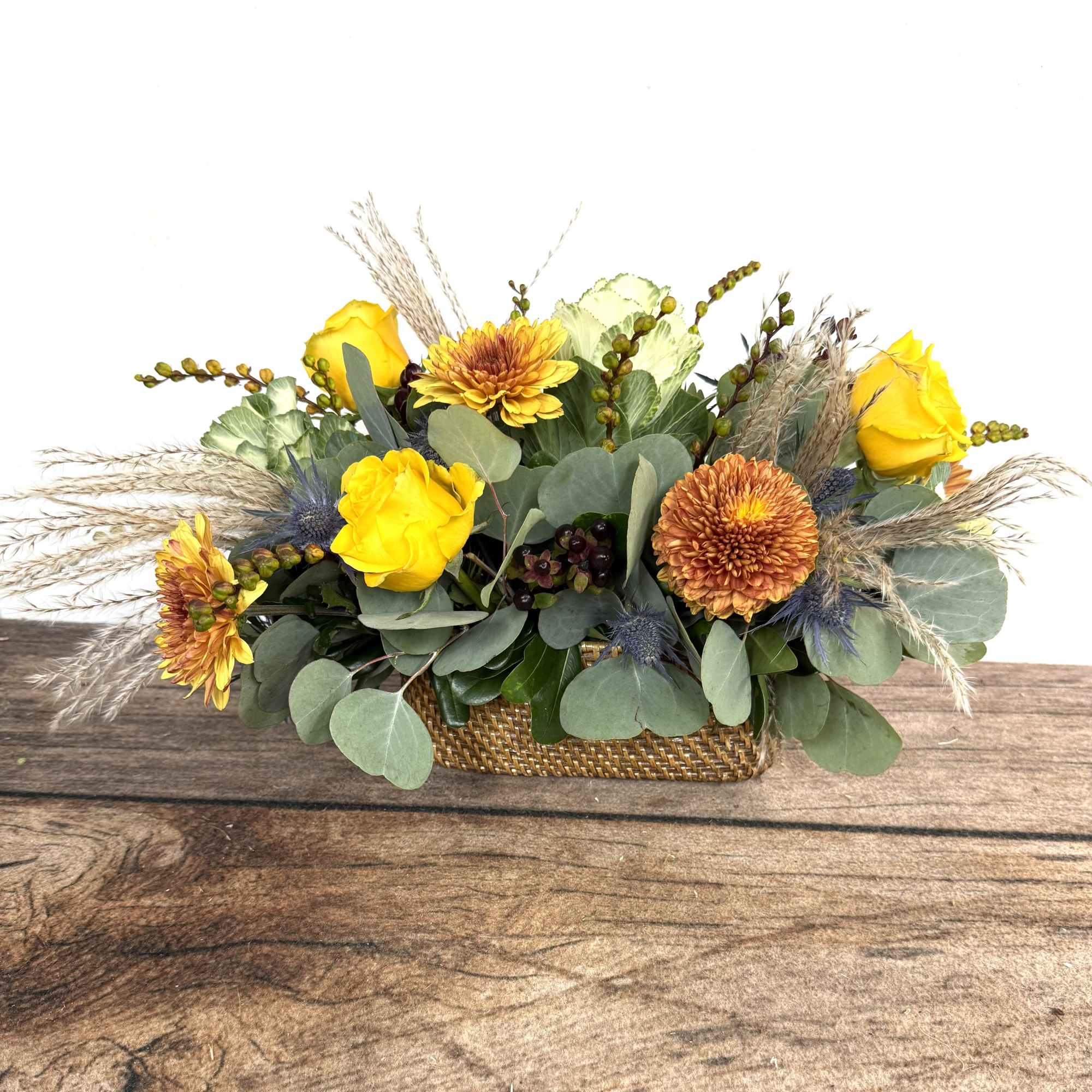 An earthy arrangement with dried accents in a contemporary, woven container. 