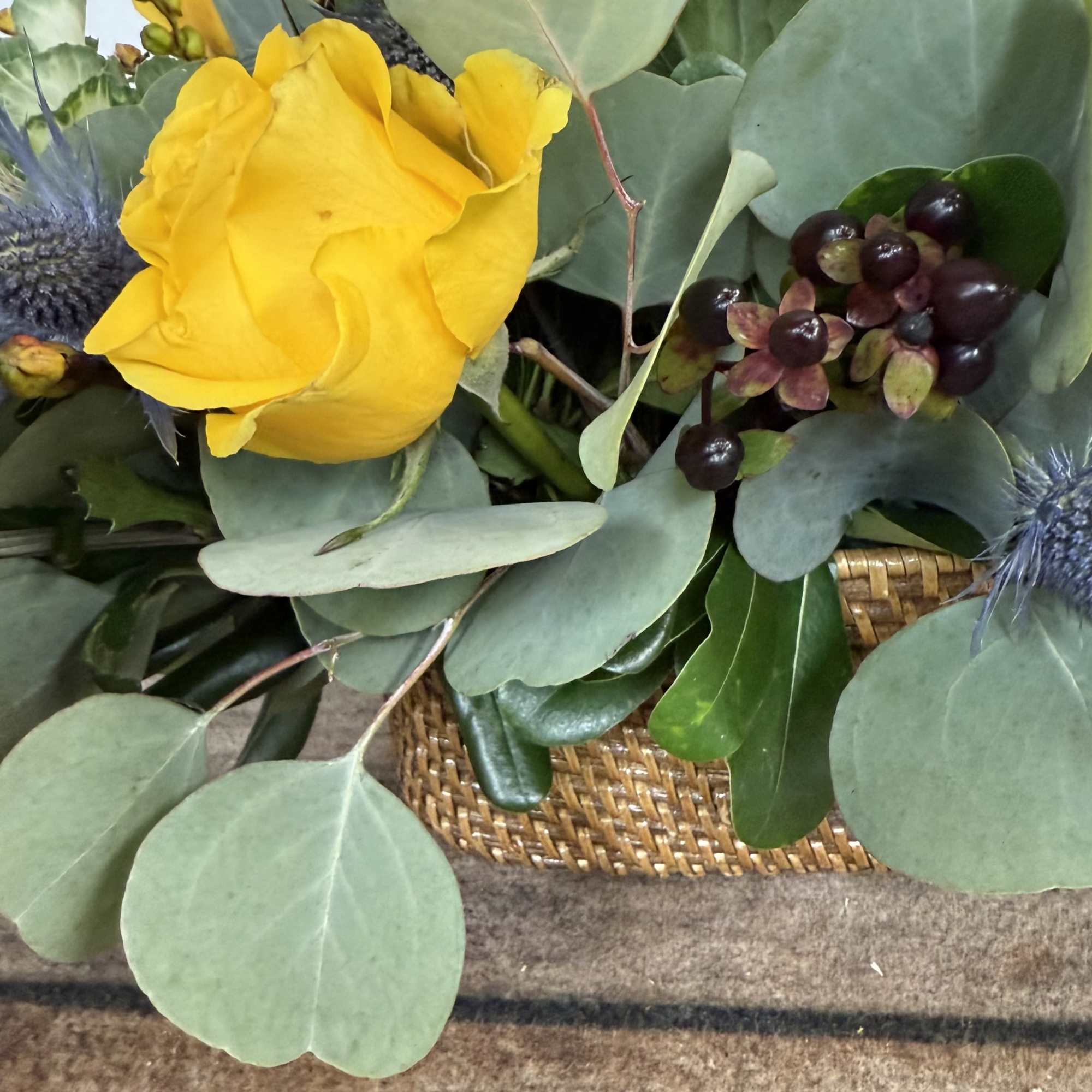 An earthy arrangement with dried accents in a contemporary, woven container. 