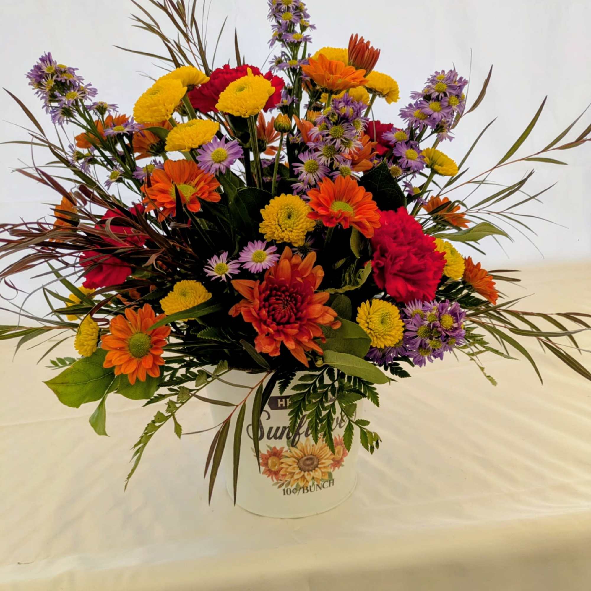 A vibrant mixed fall arrangement bursting with color and texture Arranged in