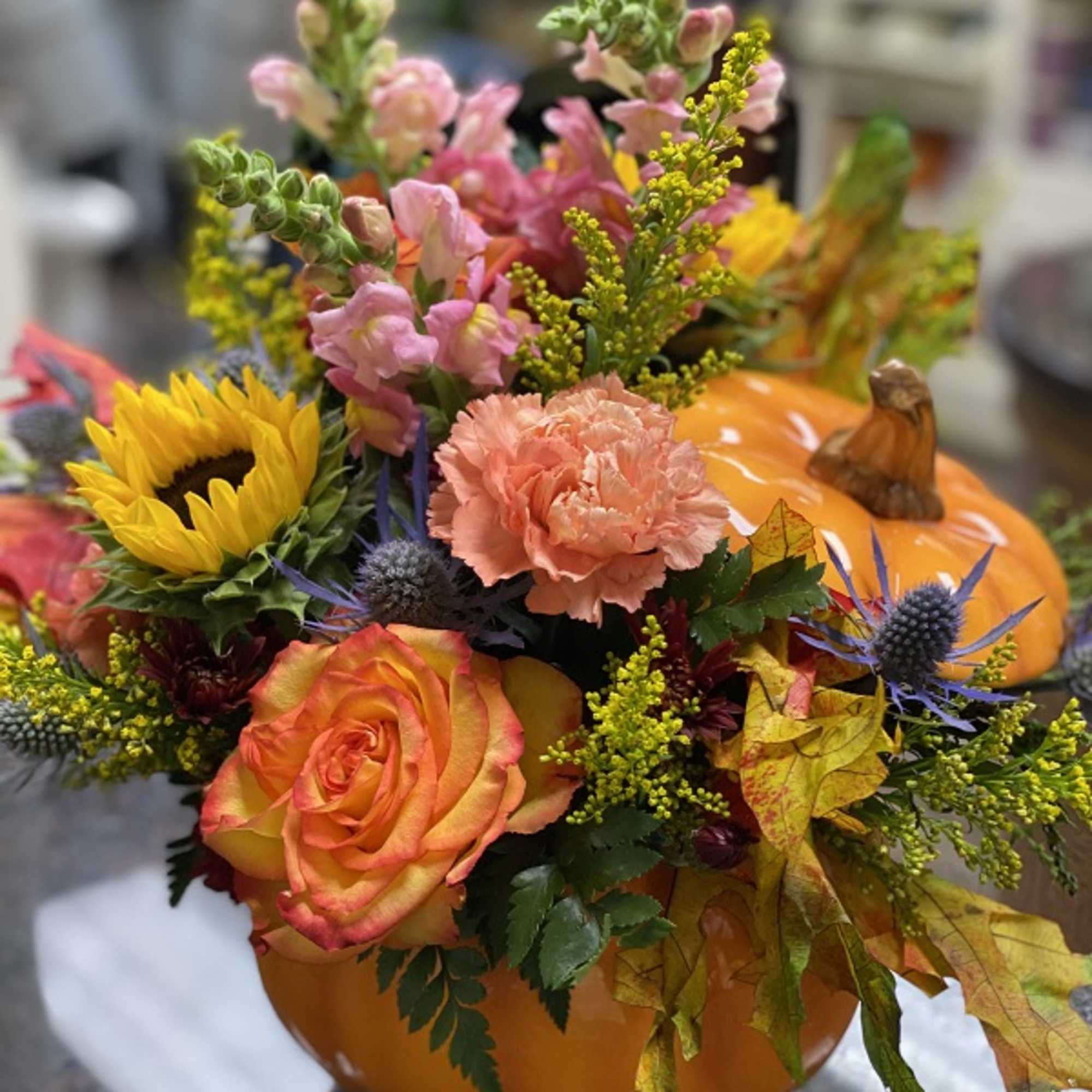 Bright fall flowers, leaves and more fill a hand-painted ceramic pumpkin that