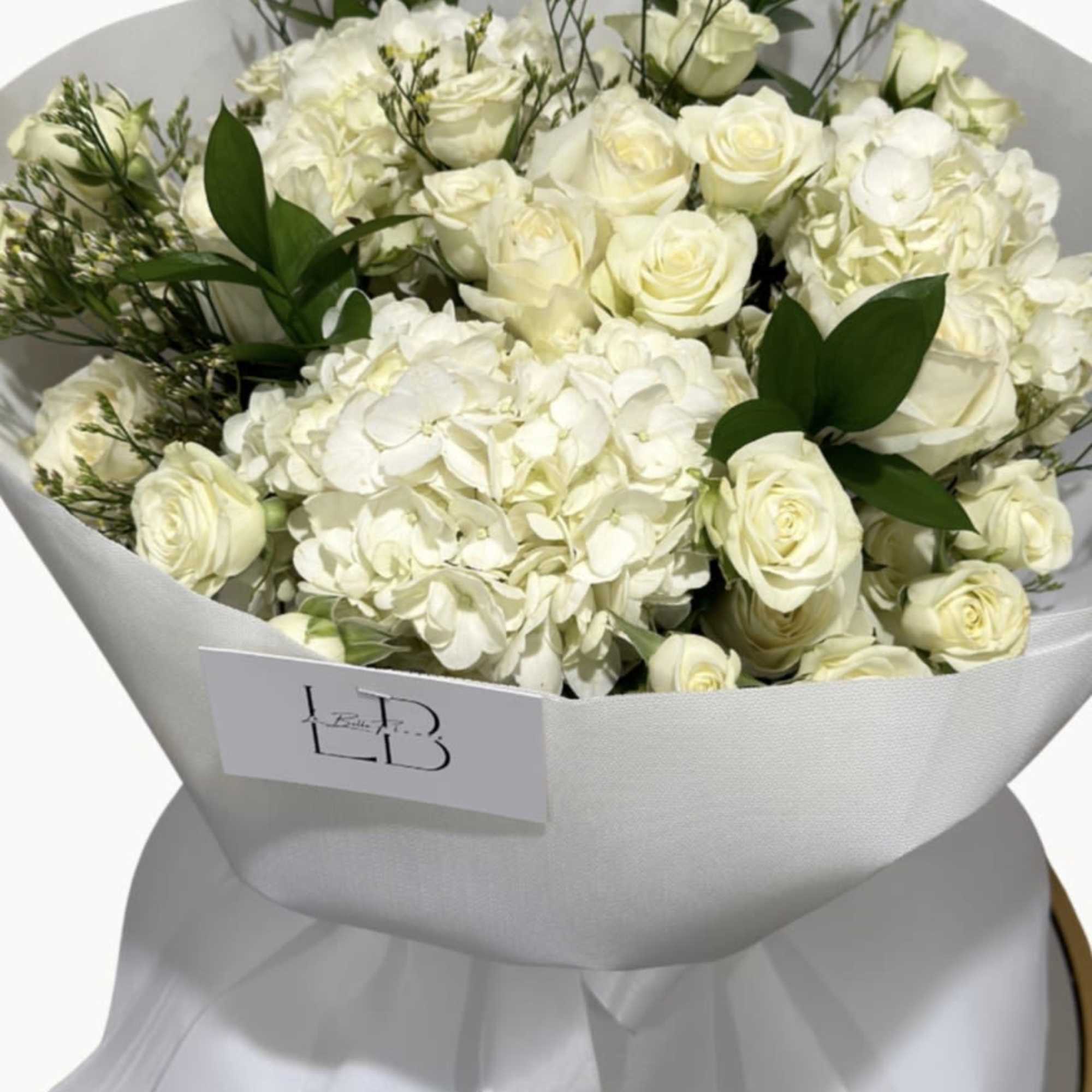New beginnings deserve flowers! This all white arrangement includes roses, lisianthus and