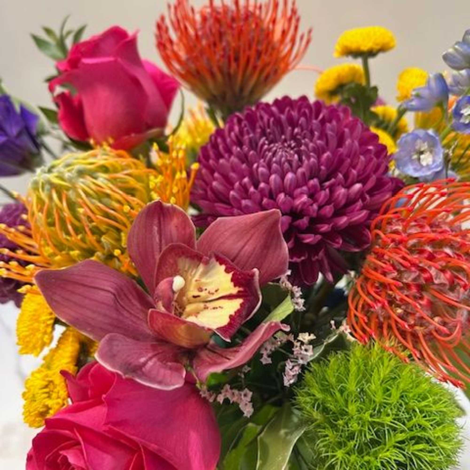 An elegant arrangement featuring a striking orchid bloom atop a vibrant mix