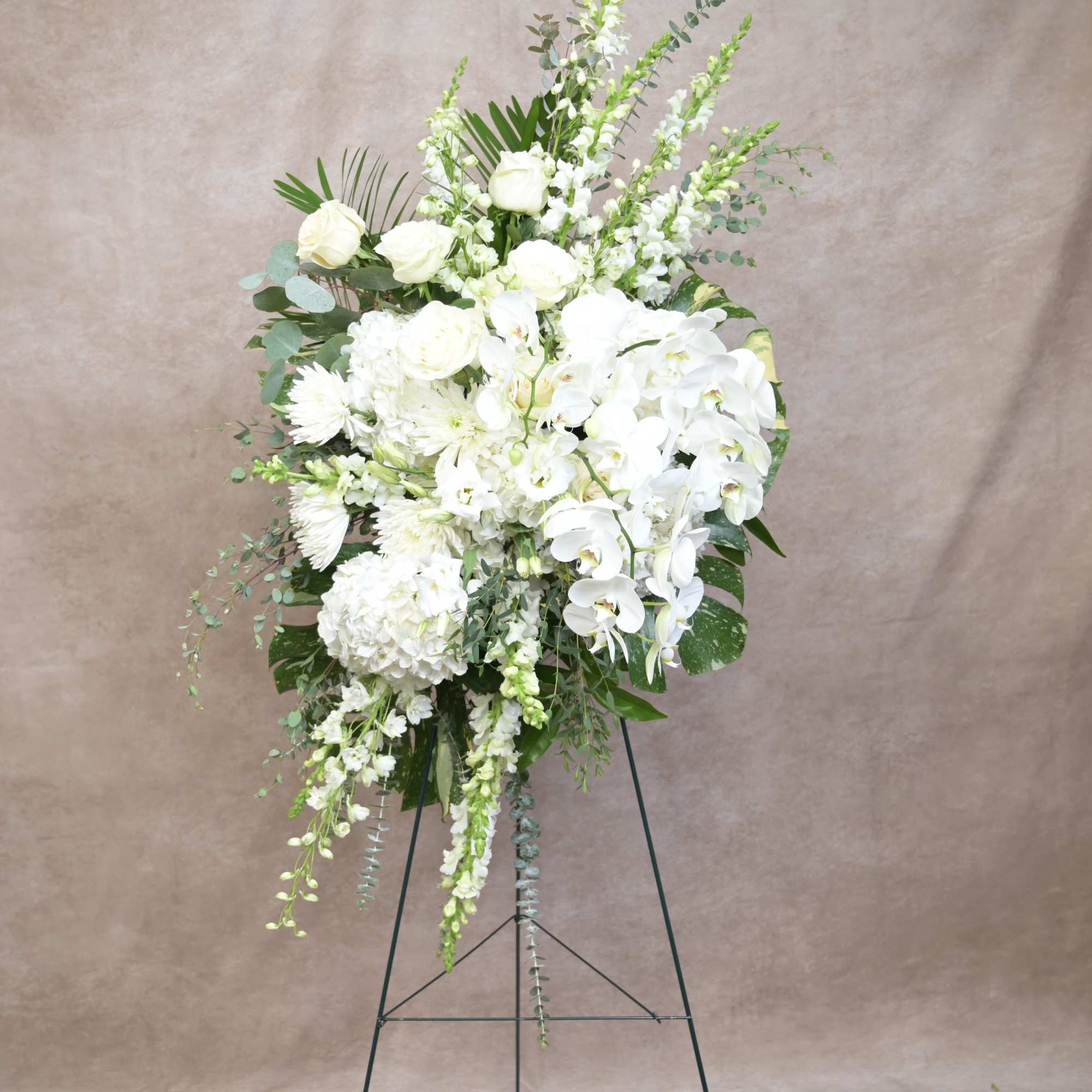 Elegant standing arrangement in a graceful all-white palette, designed to convey peace