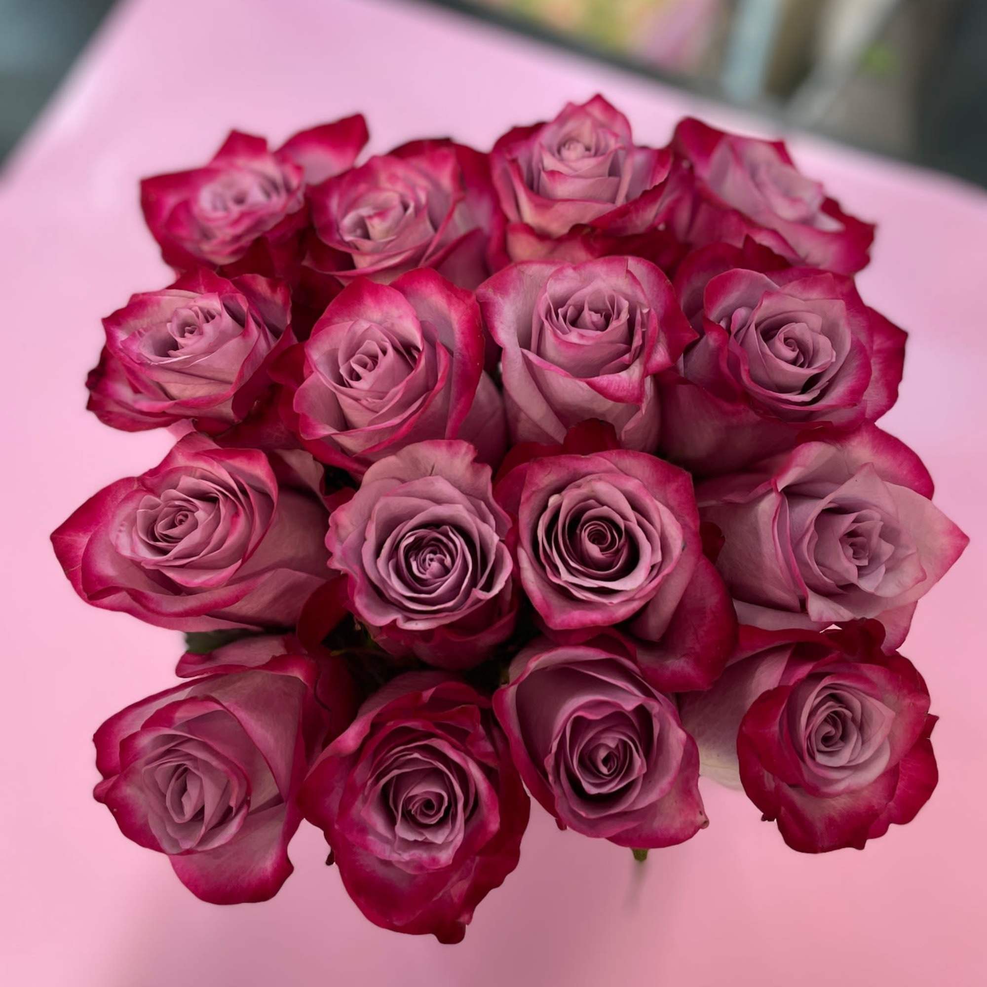 Purple Roses arranged in 6X6 Glass vase lined and decorative pebbles 