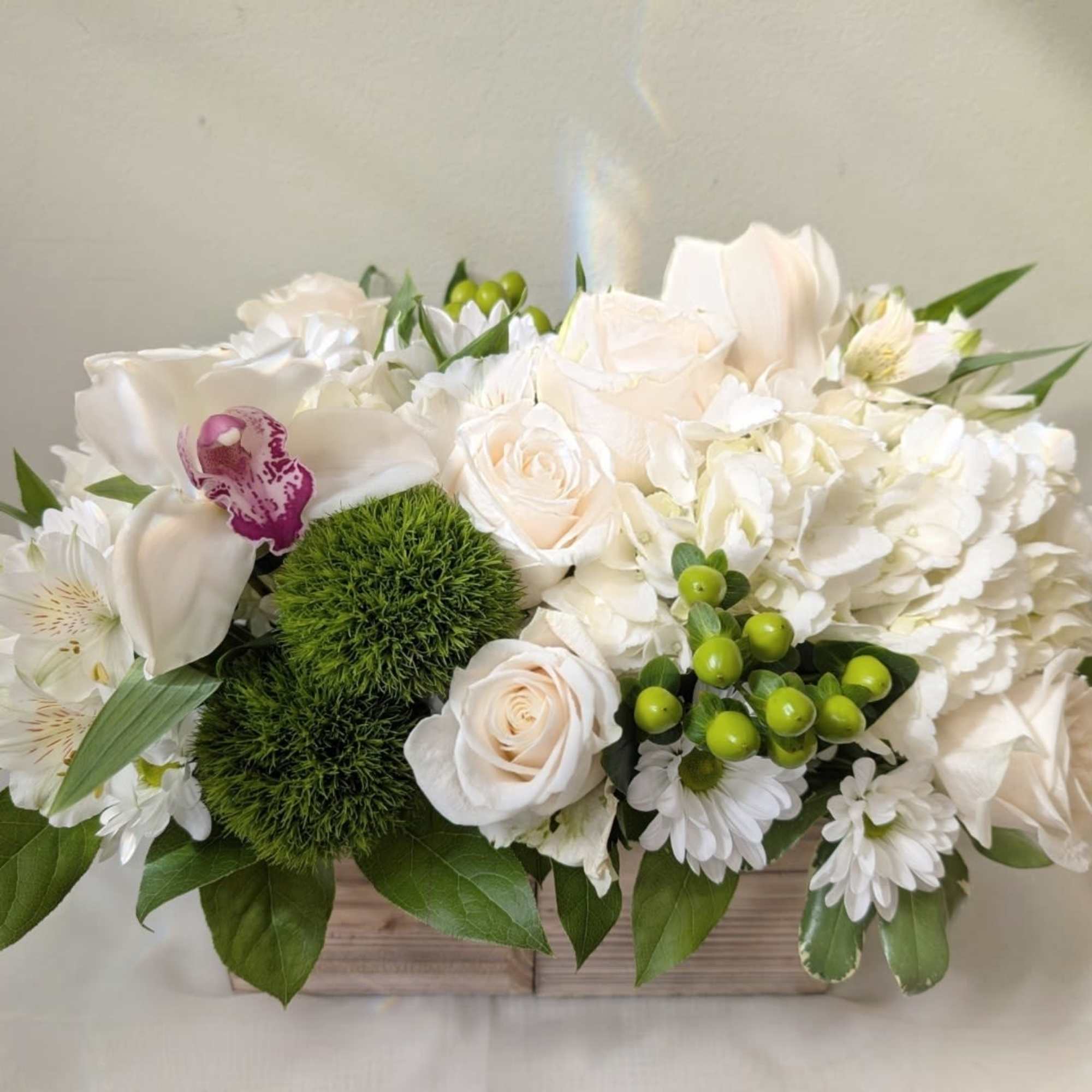 This crisp white and green arrangement includes roses, dianthus, and hydrangeas. The