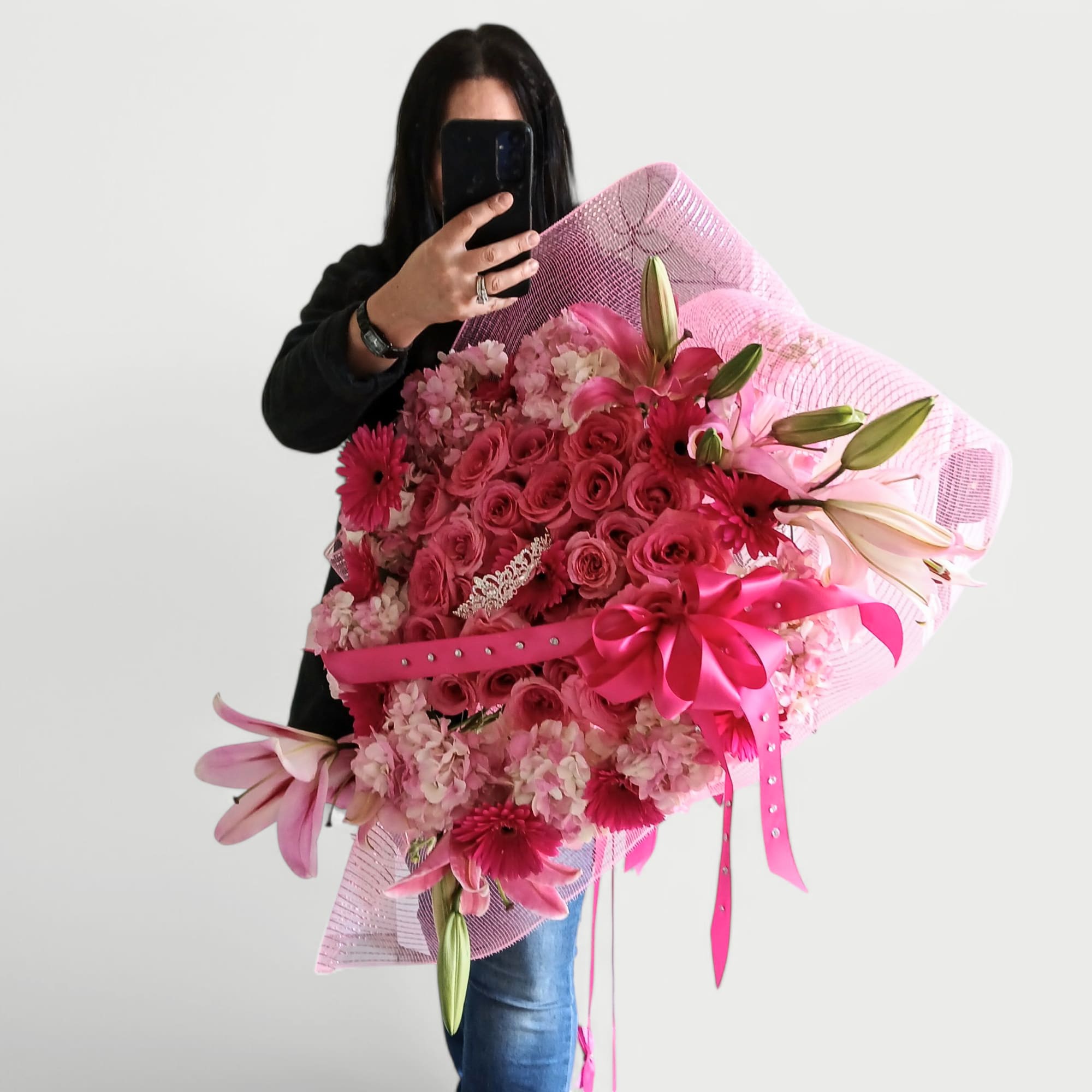 Stunning and pink with roses hydrangeas daisies lilies and a rhinestone tiara.