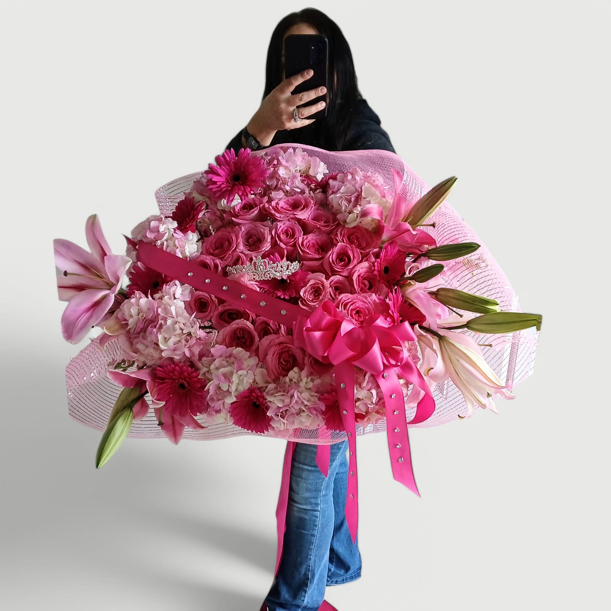 Stunning and pink with roses hydrangeas daisies lilies and a rhinestone tiara.