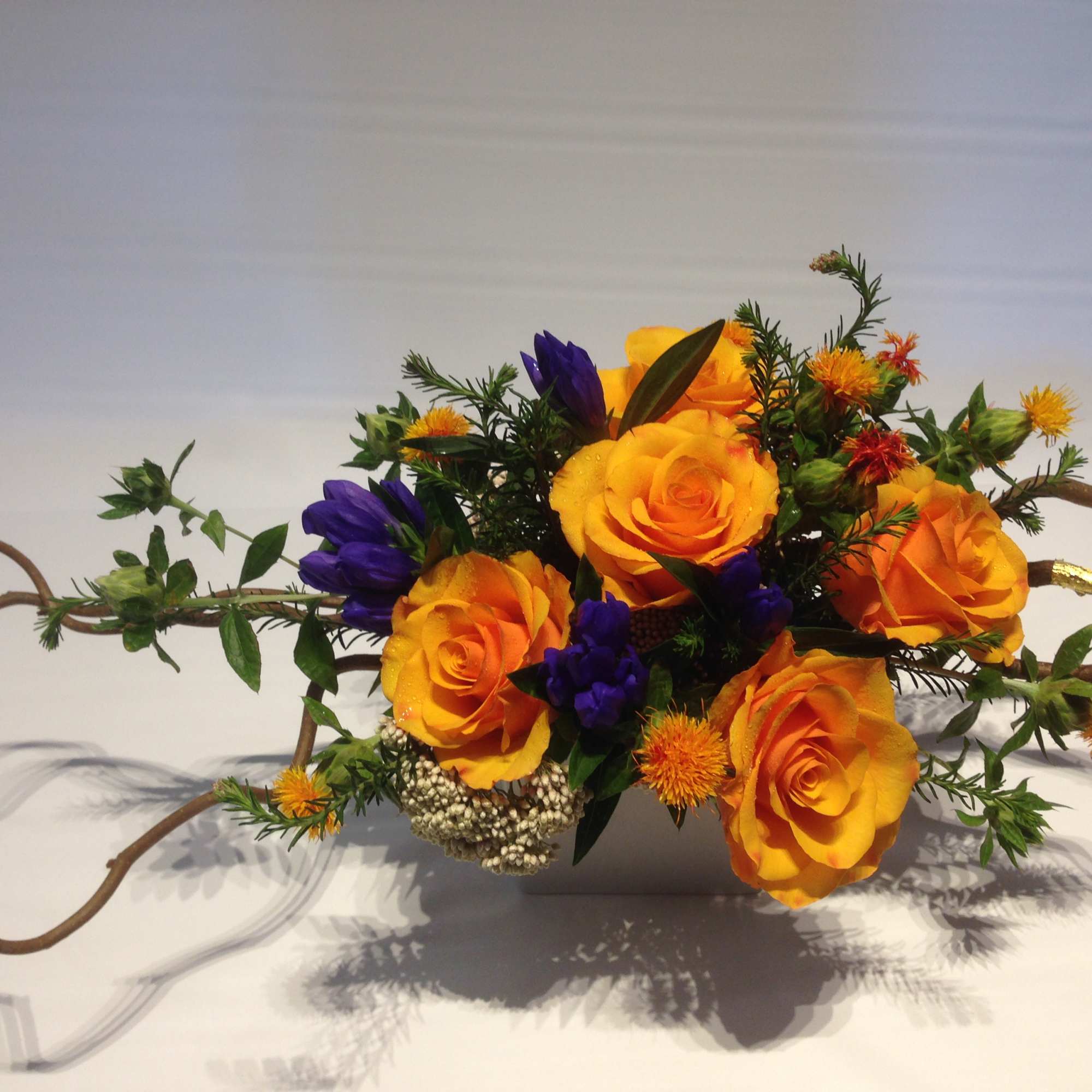 Long and low design with orange garden roses, touch of purple Himalayan