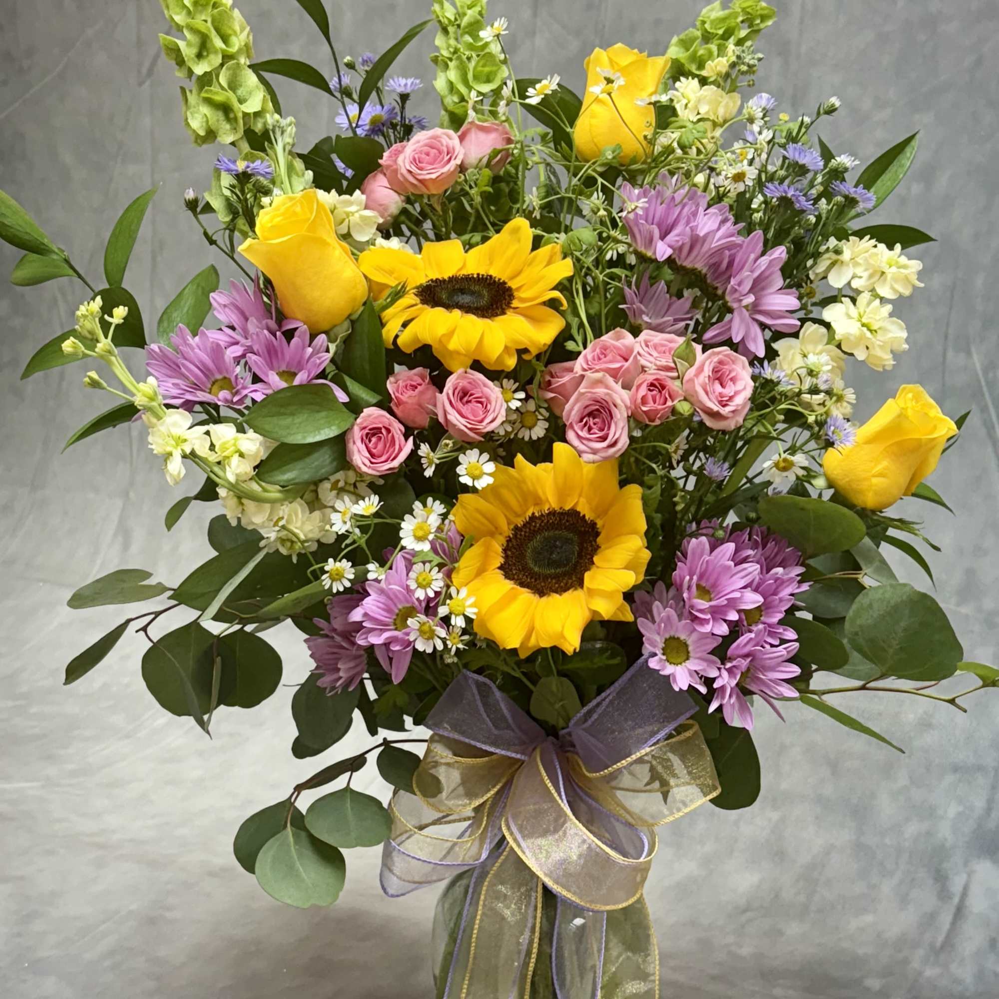 A radiant mix of golden sunflowers, sunny yellow roses, delicate pink spray