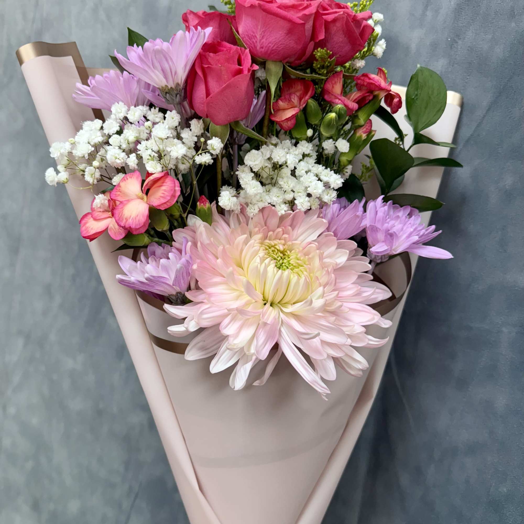 Our petite Pink Breeze hand-tied bouquet features cheerful mums, spray roses, daisies