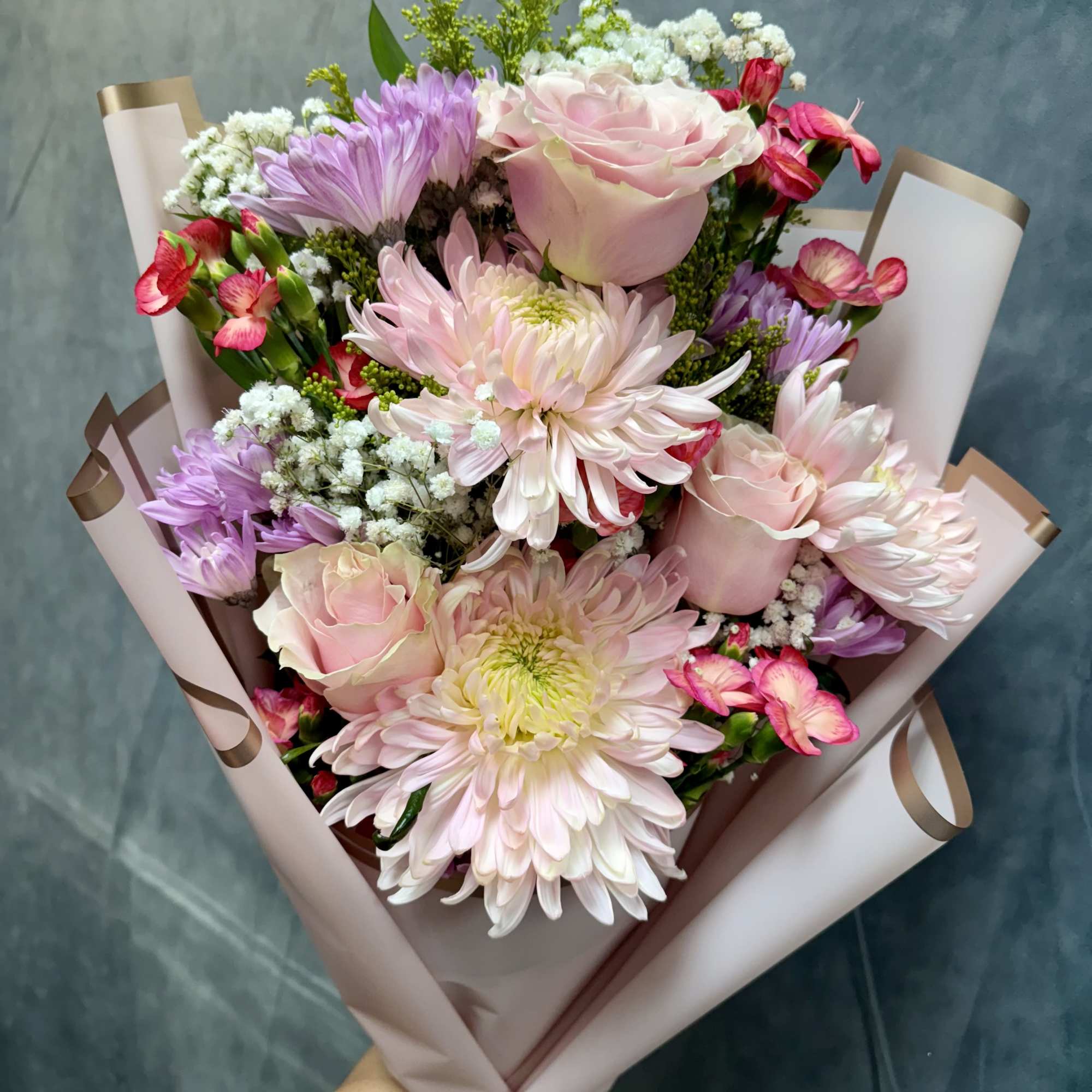Our petite Pink Breeze hand-tied bouquet features cheerful mums, spray roses, daisies