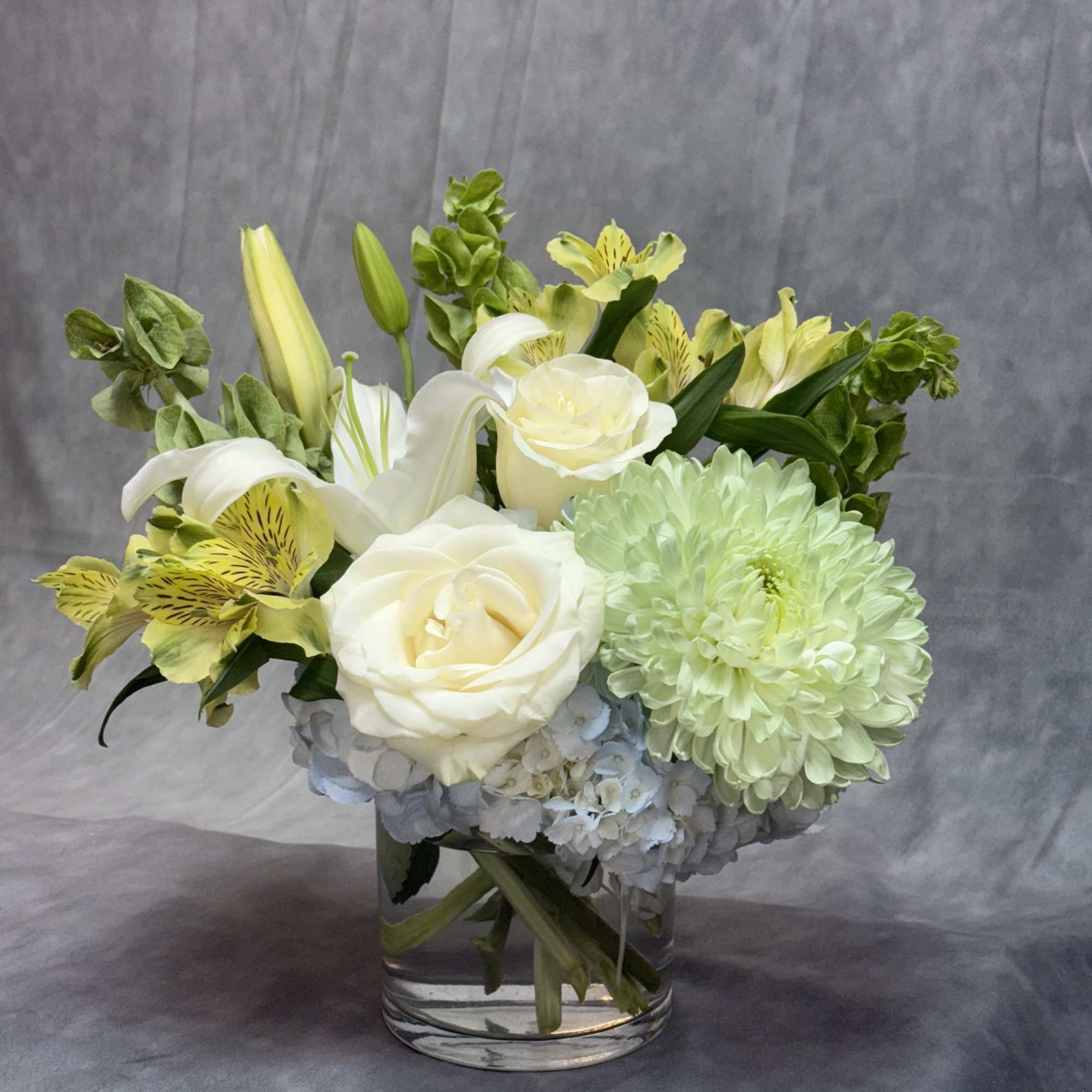 A graceful arrangement blending soft blue hydrangeas, elegant white lilies, creamy white