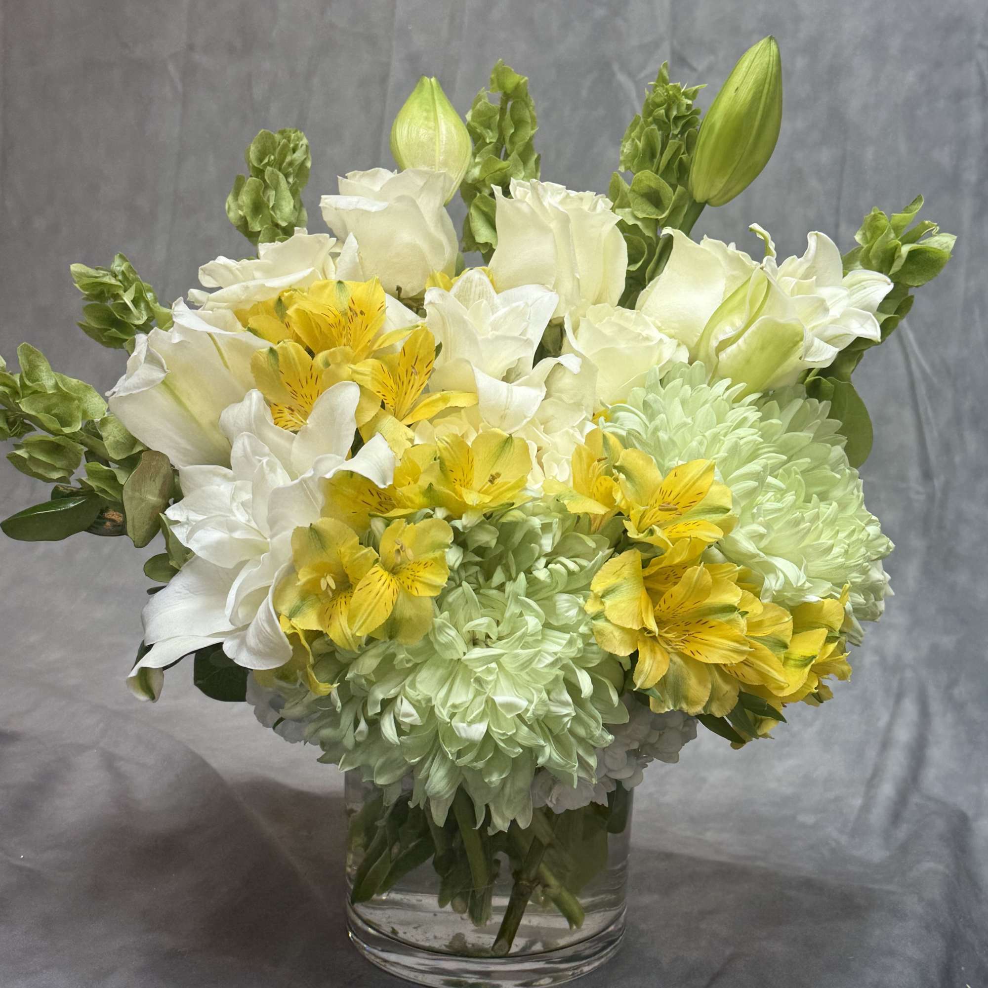A graceful arrangement blending soft blue hydrangeas, elegant white lilies, creamy white