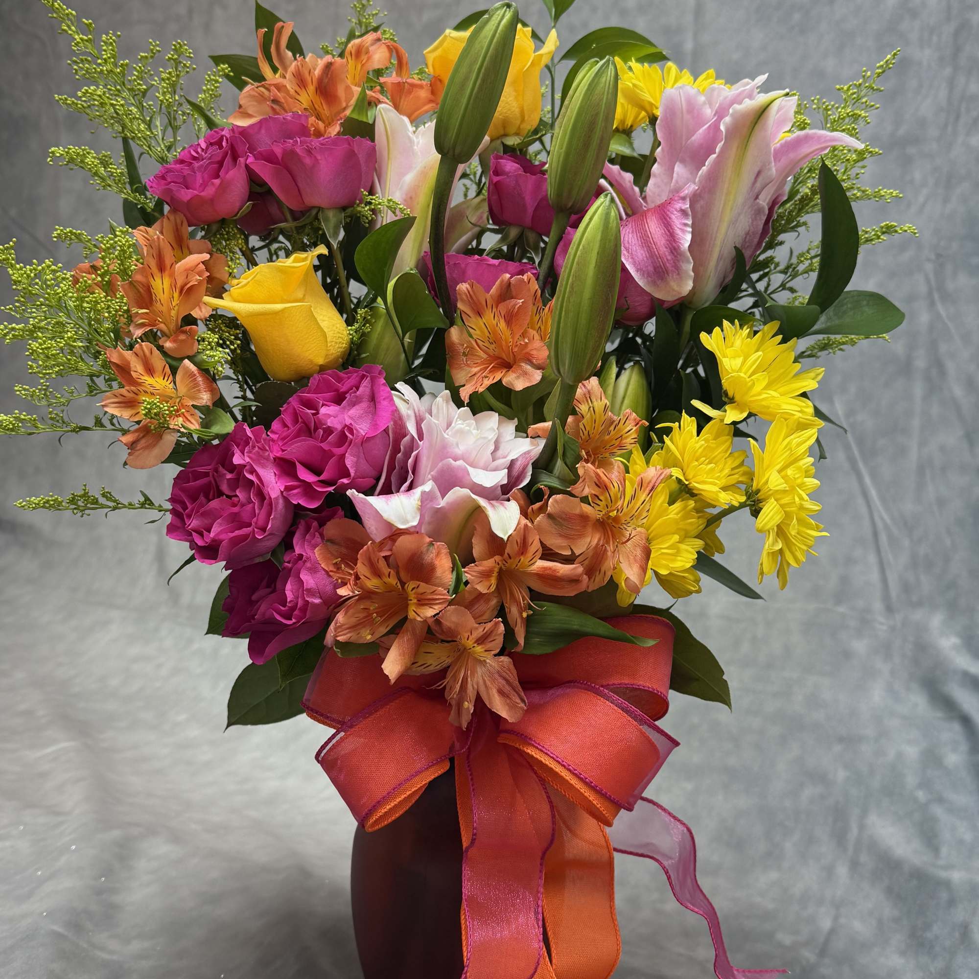 A bright and cheerful small vase featuring warm orange lilies, lively orange