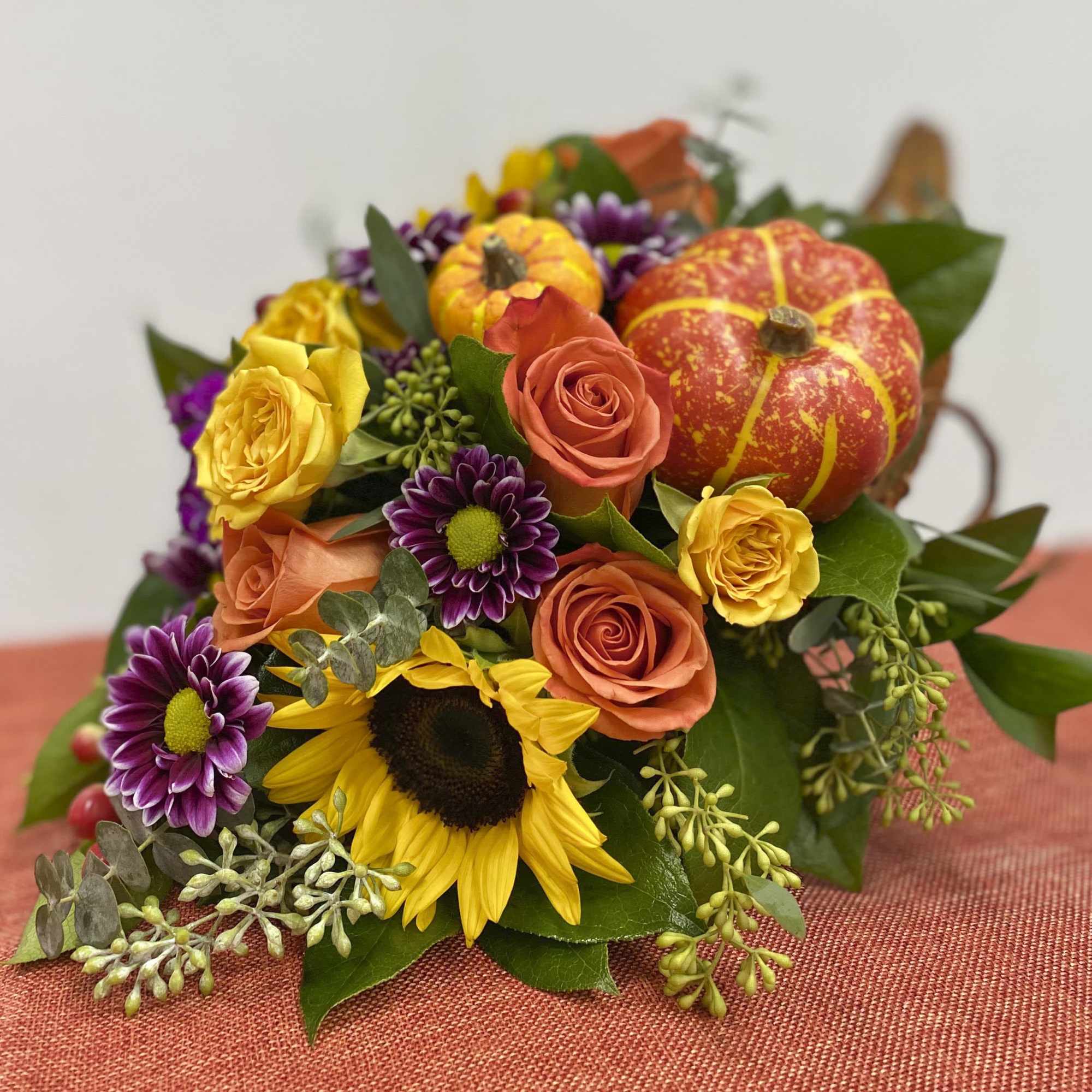 Our Fall arrangement comes with sunflower seeded euc, baby euc, roses, daisy&#039;s