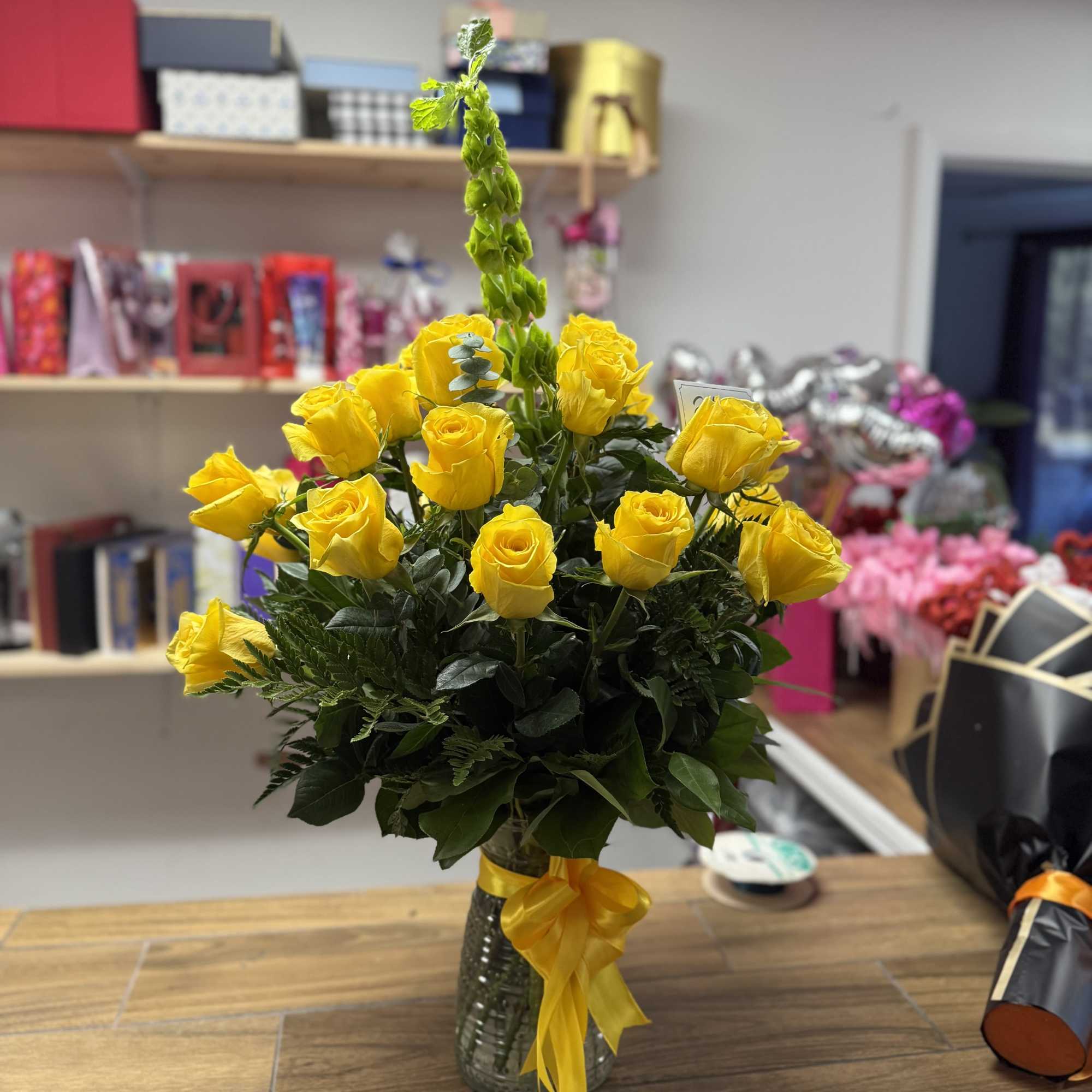 Glass vase with a 25 Yellow roses  and fine foliages. 