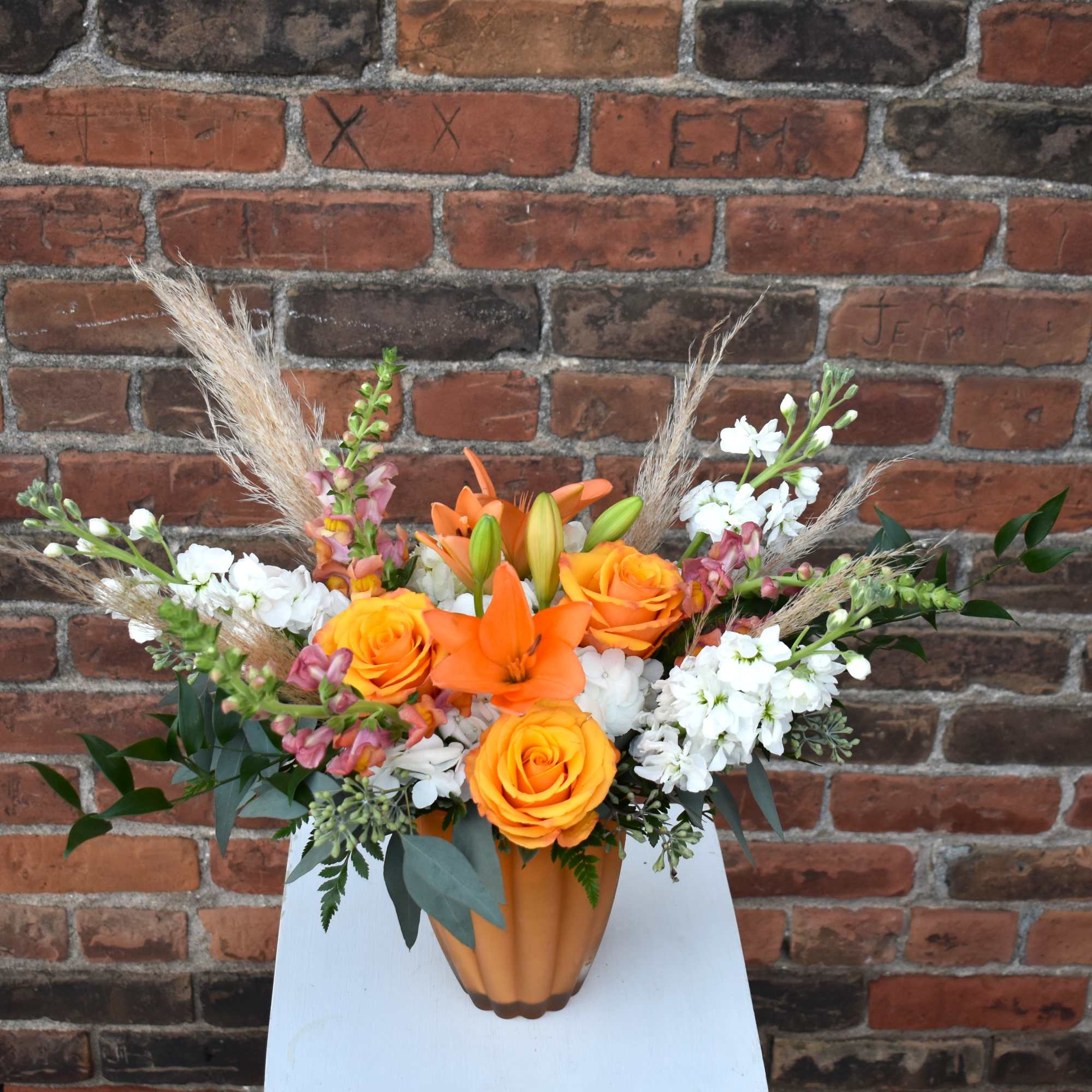 A delightful fall bouquet brimming with vibrant orange snapdragons, roses, lilies, white