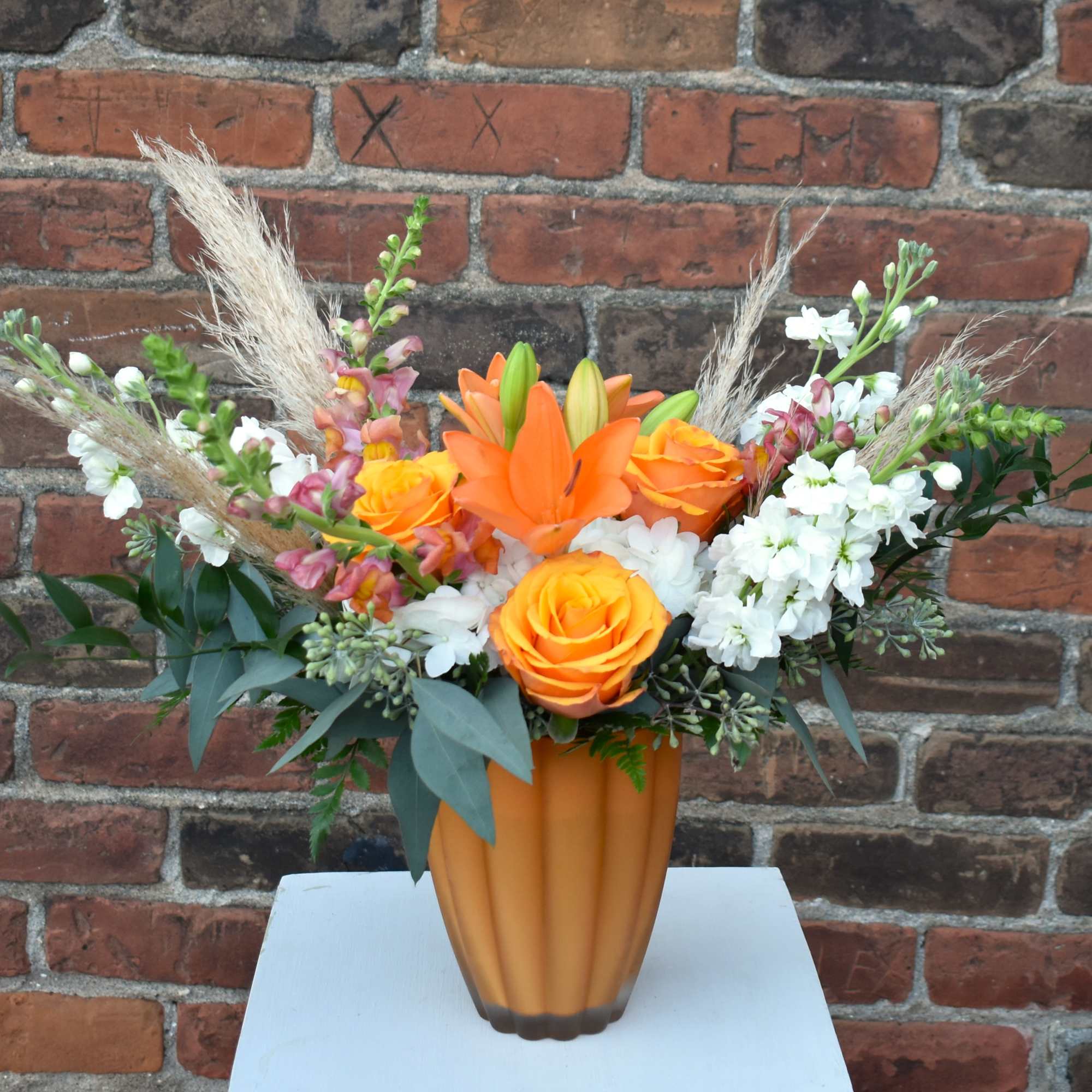 A delightful fall bouquet brimming with vibrant orange snapdragons, roses, lilies, white