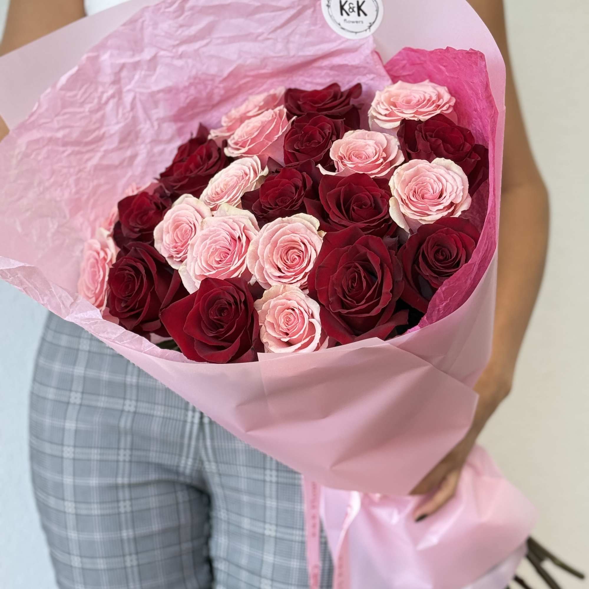 Red and pink roses, accompanied by greenery and decorative wrapping paper. All