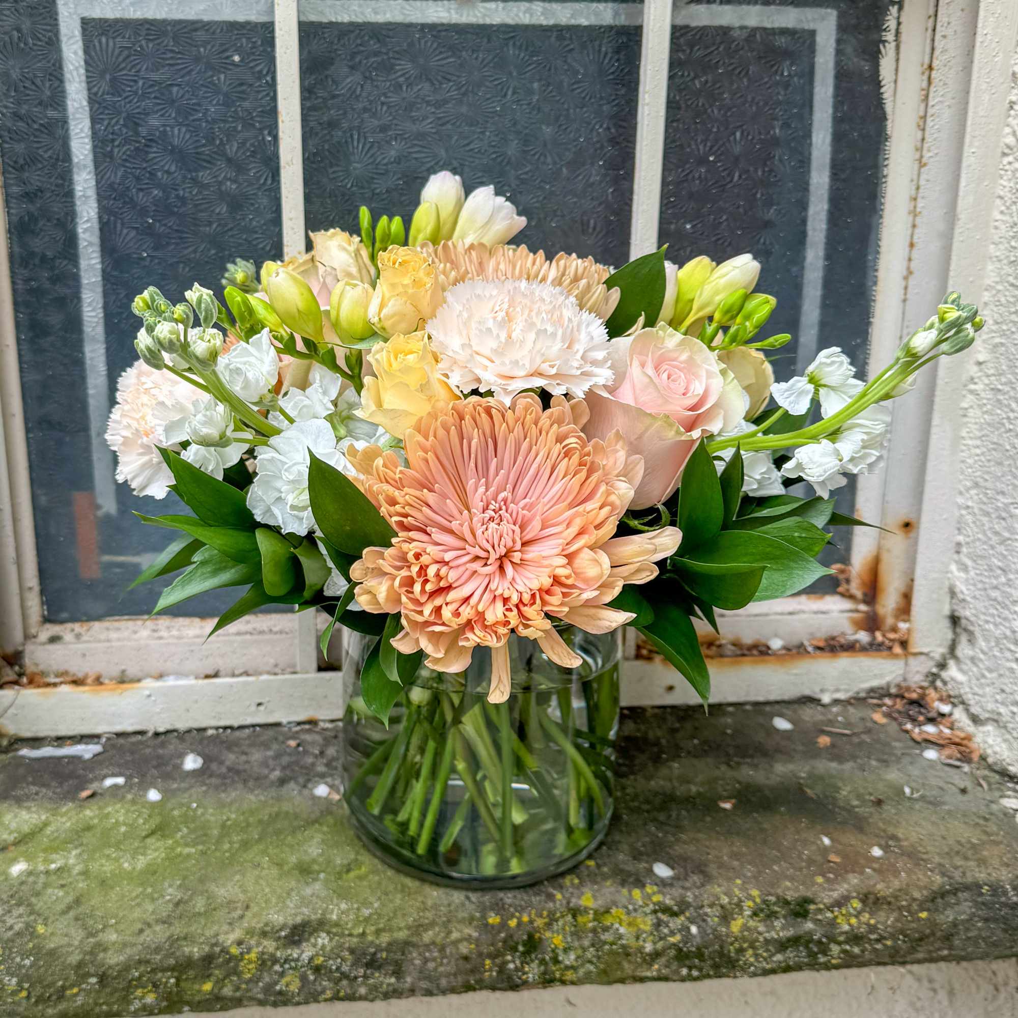 Maman features Peach Chrysanthemums, Blush Roses, Peach Spray Roses, White Stock, White