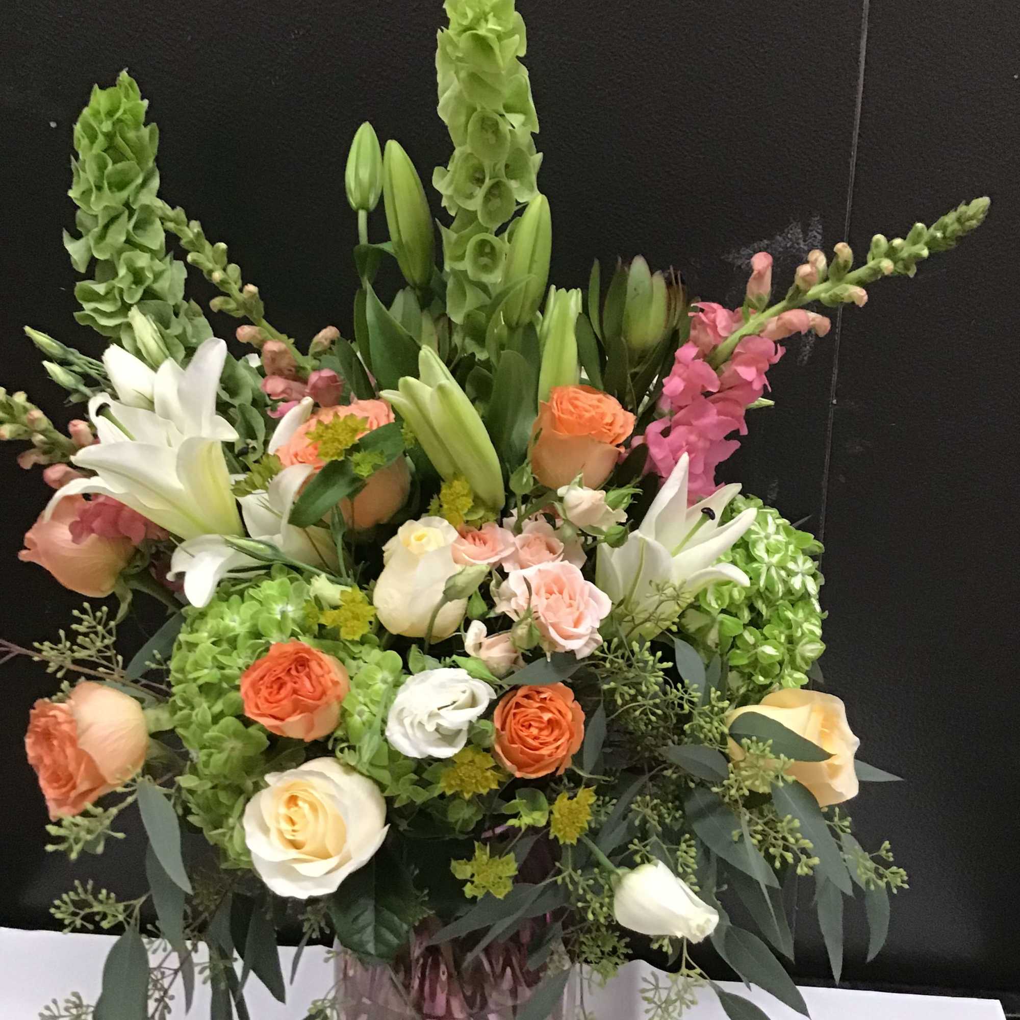 This beautiful arrangement make with peach and cream color roses, white lily