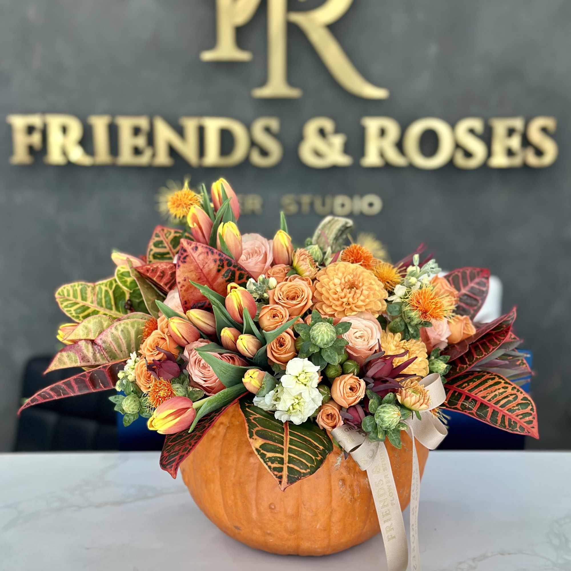 A stunning autumn arrangement featuring dahlias, roses, tulips, and seasonal greenery, elegantly